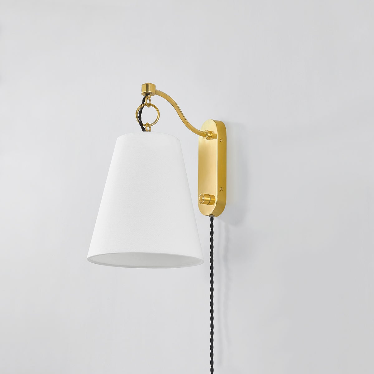 Joan Plug-In Sconce in aged brass shown from the front to reveal the arm profile and shade silhouette.