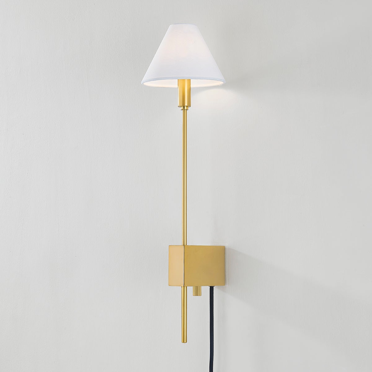 Close-up of the Teaneck Plug-In Sconce in aged brass showing the arm profile and shade silhouette.