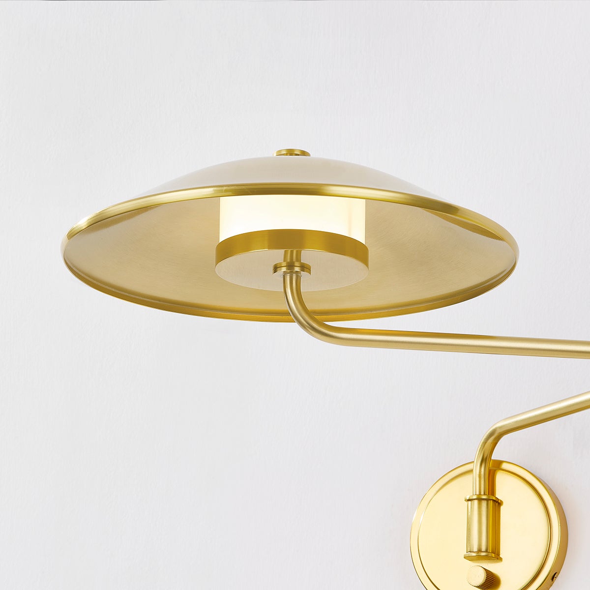 Close-up of the Brockville Wall Sconce in aged brass showing the arm curve and shade silhouette.