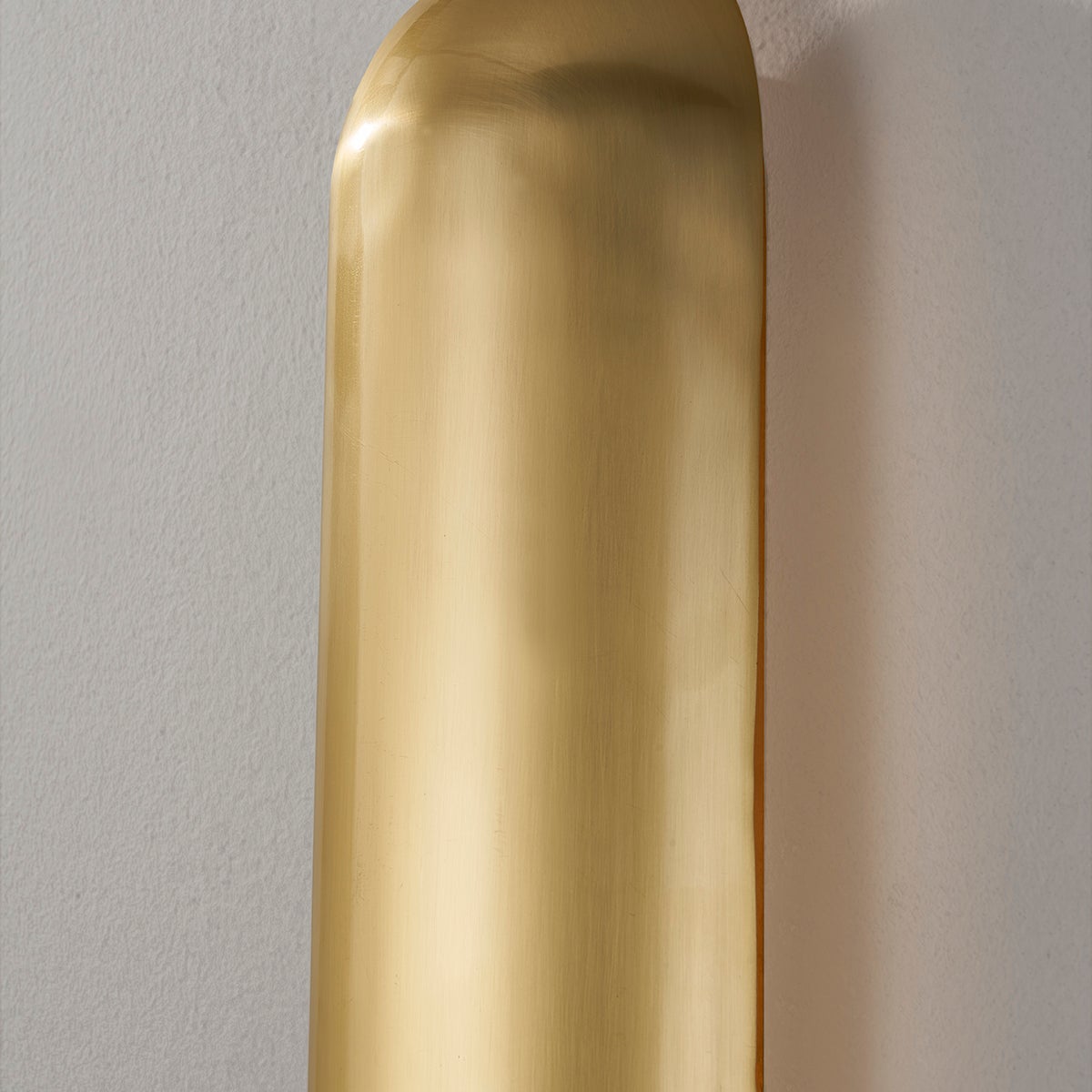 Close-up of the Wheeler Wall Sconce in aged brass showing the arm curve and shade silhouette.