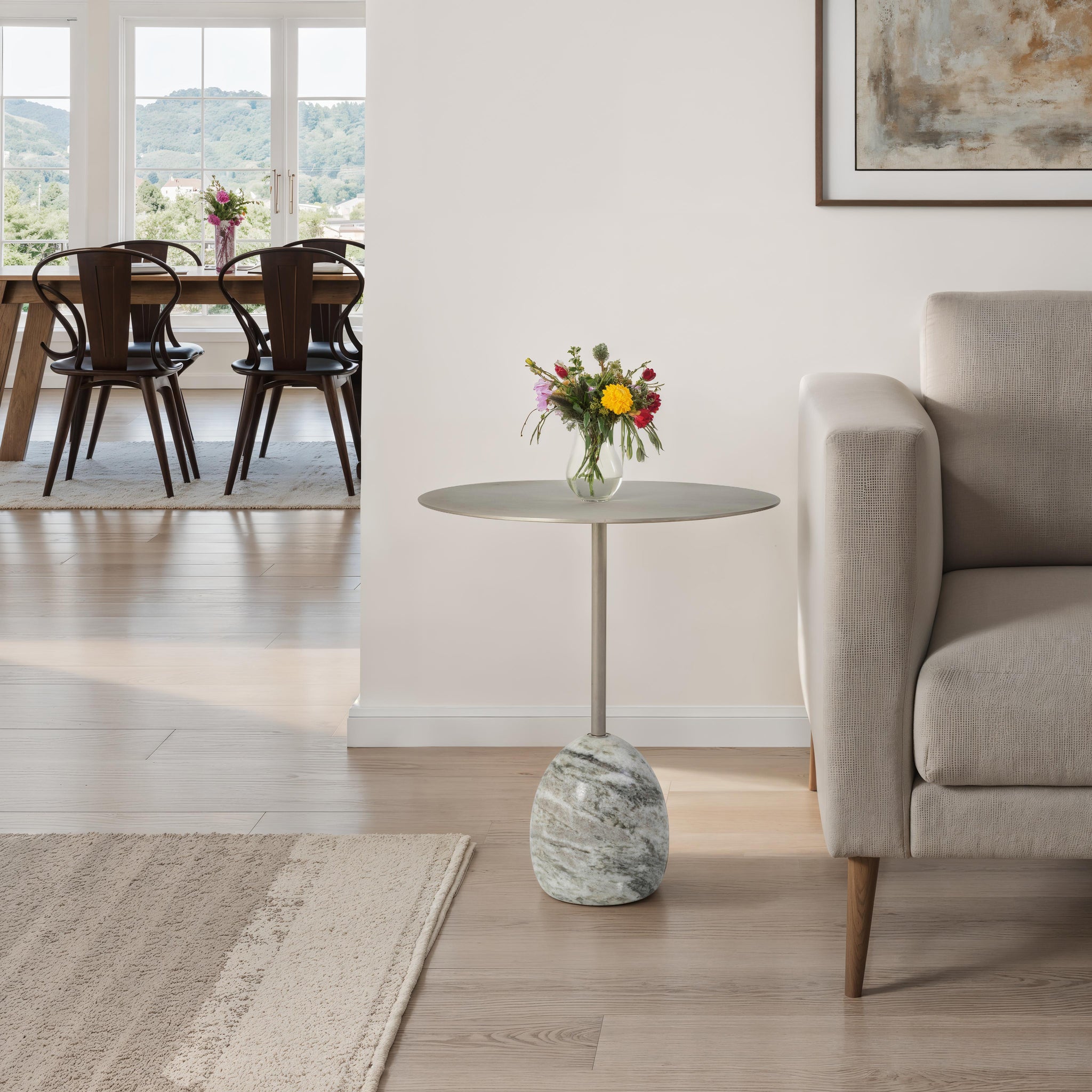 Aiden side table placed beside a sofa with a vase of flowers on top in a bright living room.