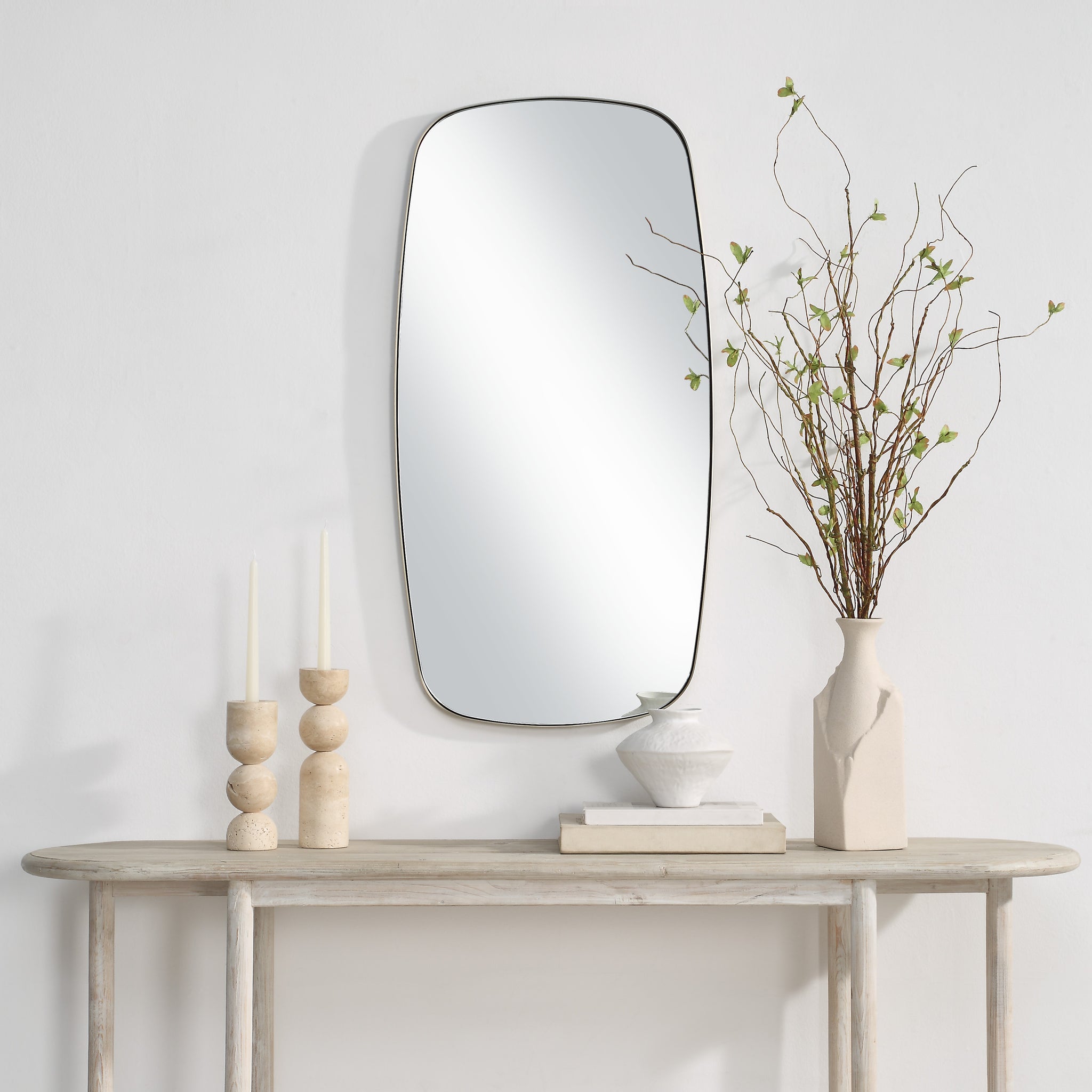 Jacossa mirror mounted on a wall above a wooden table with decorative items
