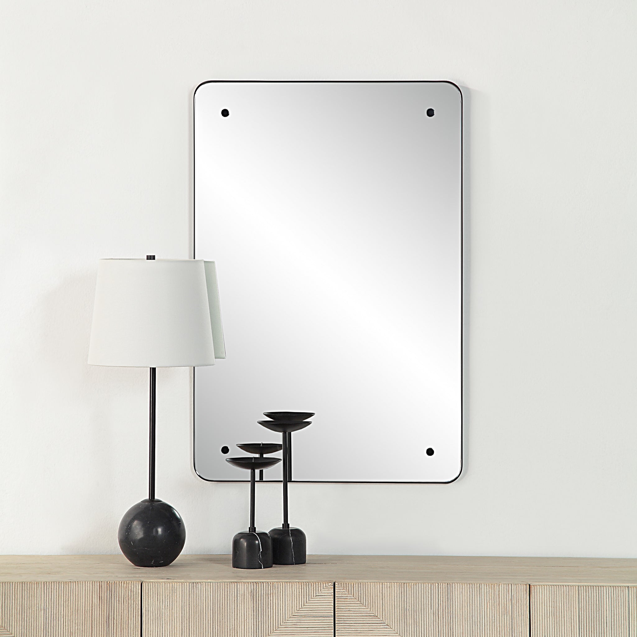 Aine Wall Mirror displayed on a wall above a wooden console with decorative items.