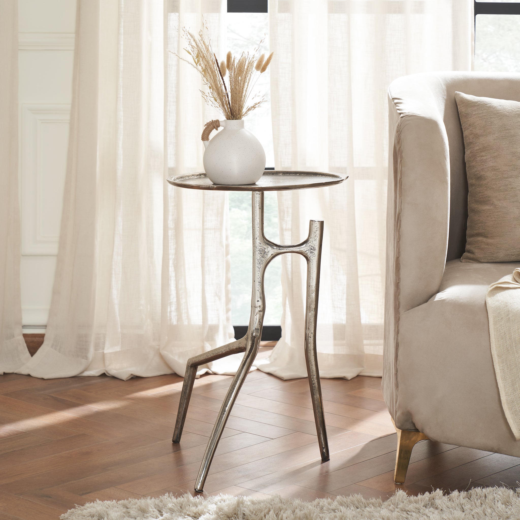 Tosco table styled with a vase and dried flowers, placed beside a sofa.