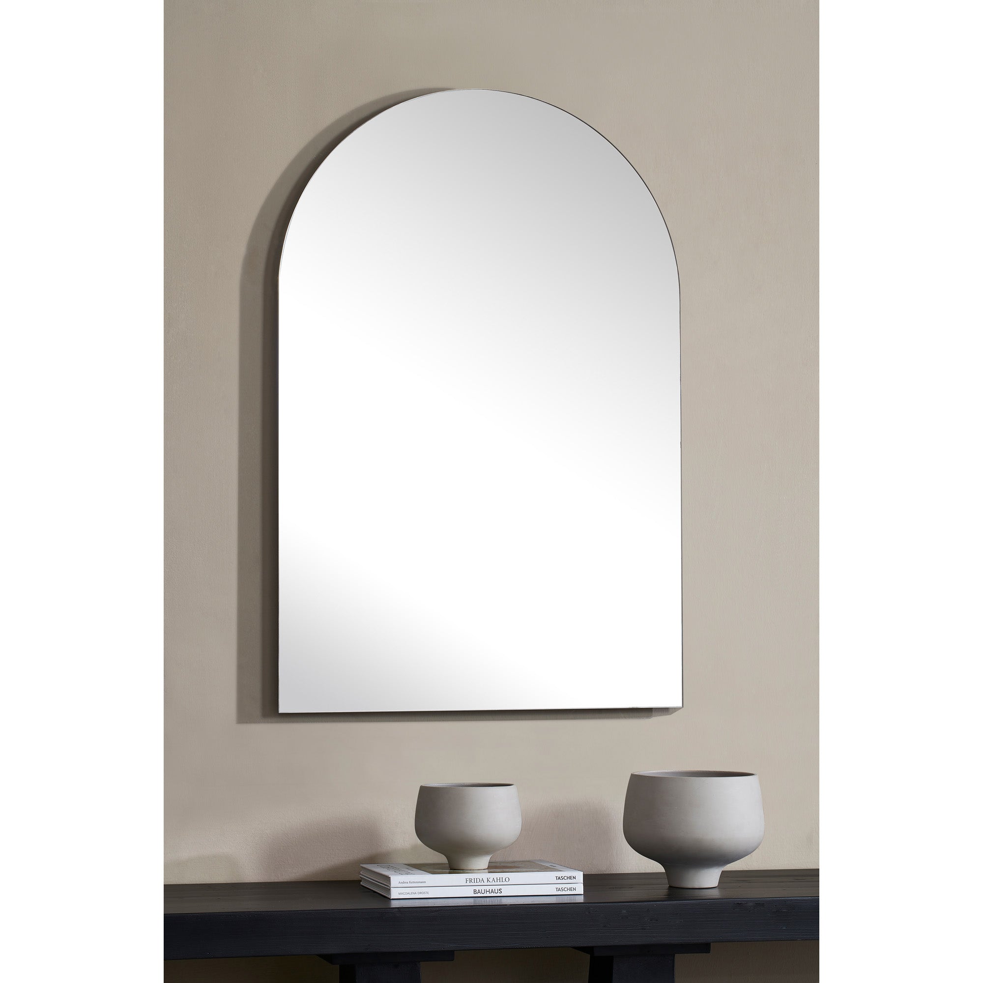 Faiza Wall Mirror displayed on a wall above a dark table with decorative vases.