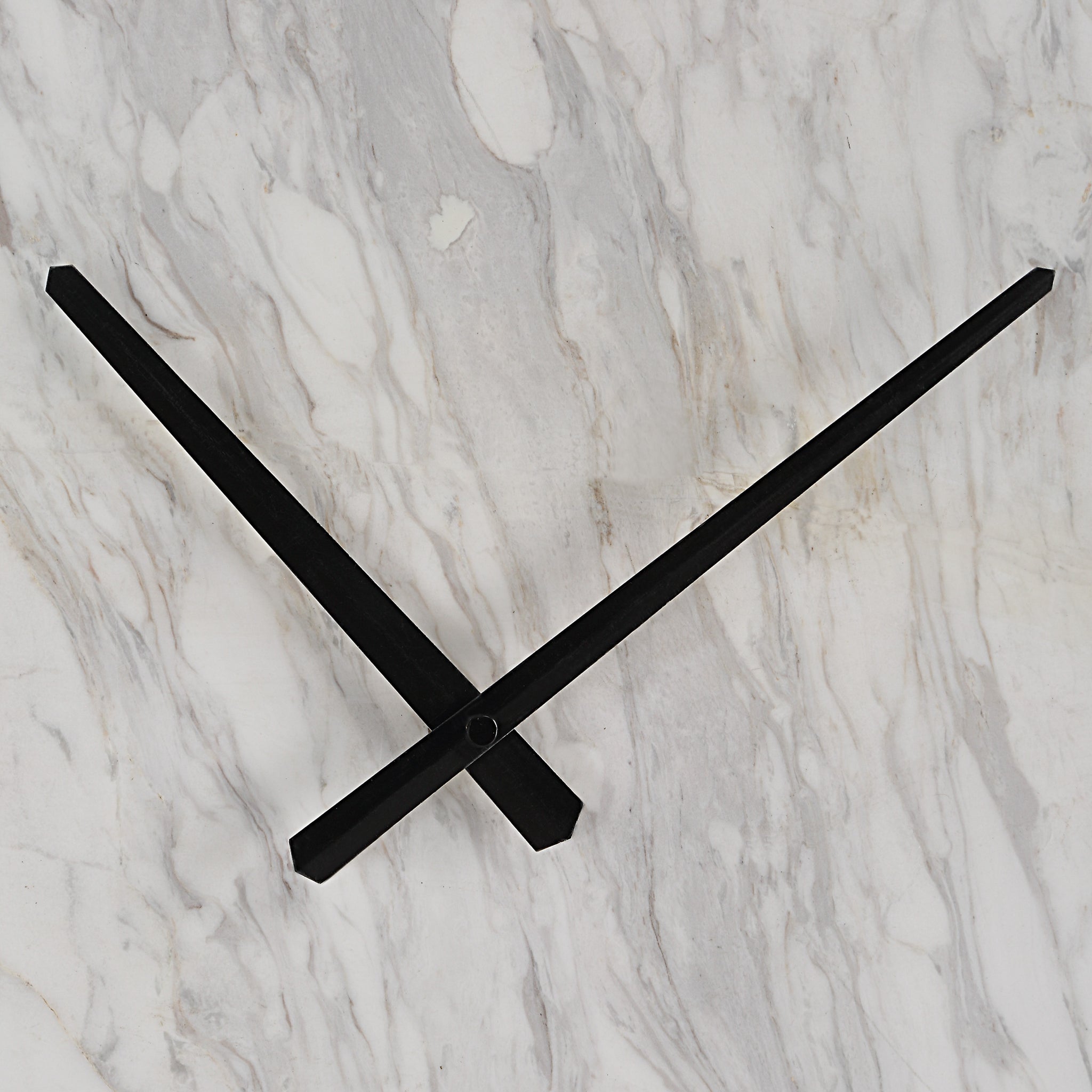 Detail view of black clock hands against a white marble background