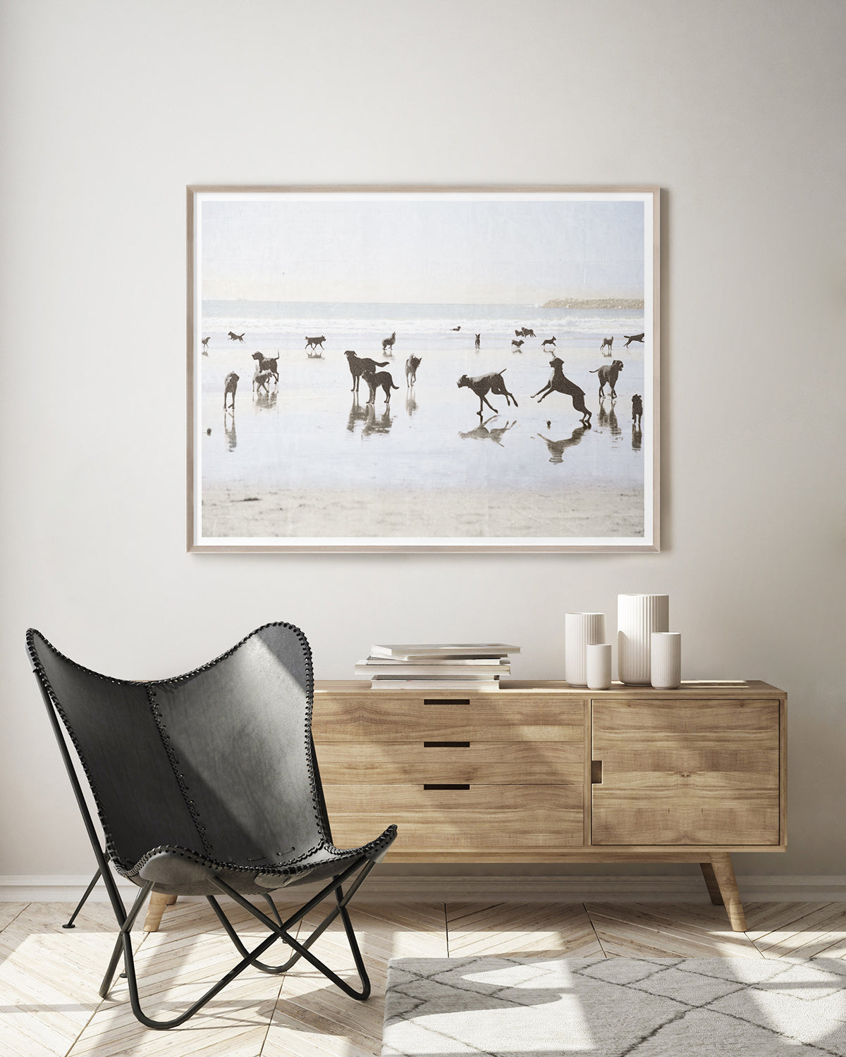 Modern interior with a black chair, wooden sideboard, and framed beach scene artwork.