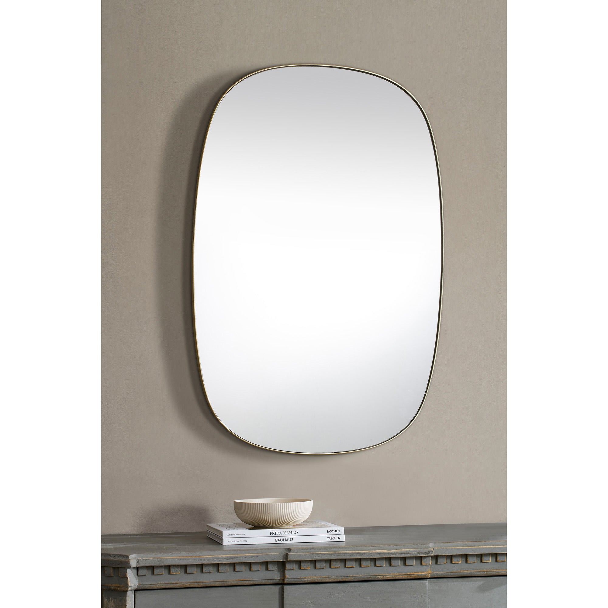 Gallegos Wall Mirror displayed on a wall above a table with decorative items.