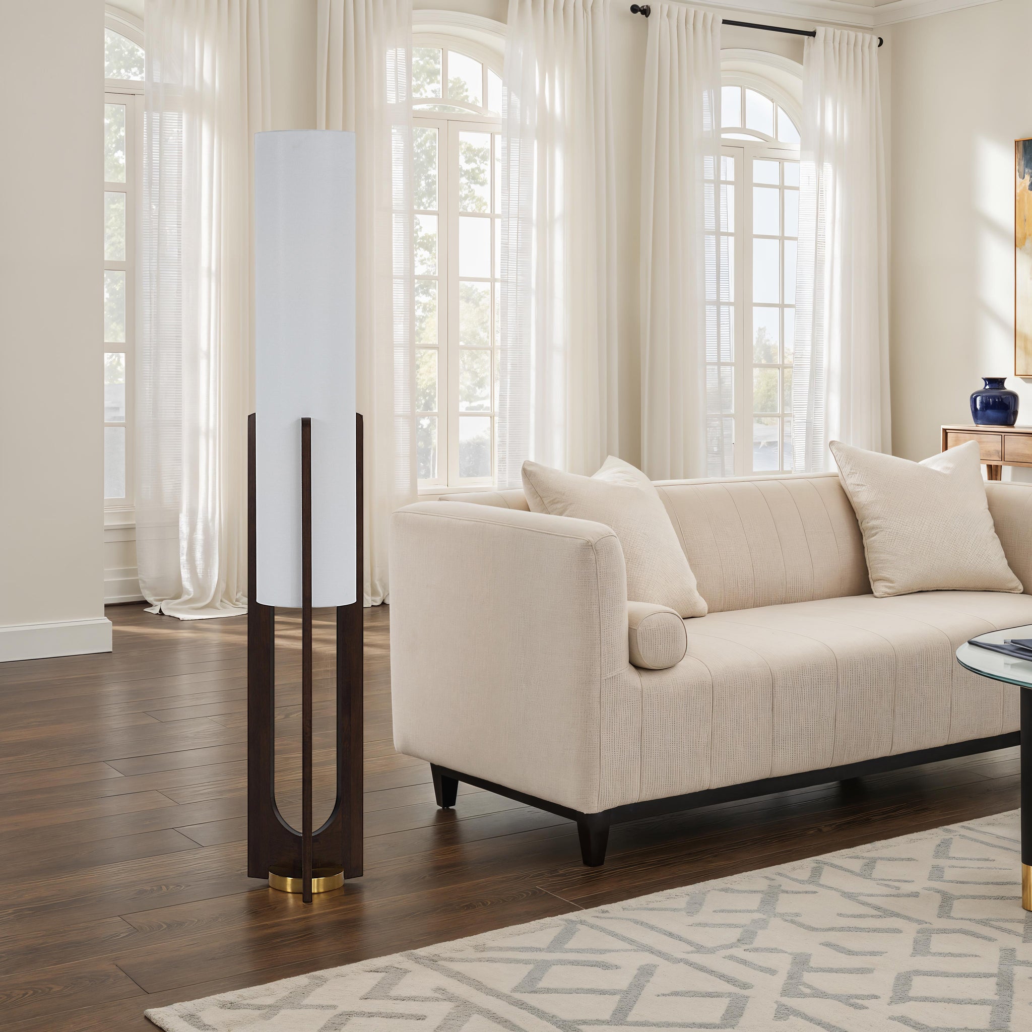 Mael floor lamp in a cozy living room setting next to a beige sofa and large windows.