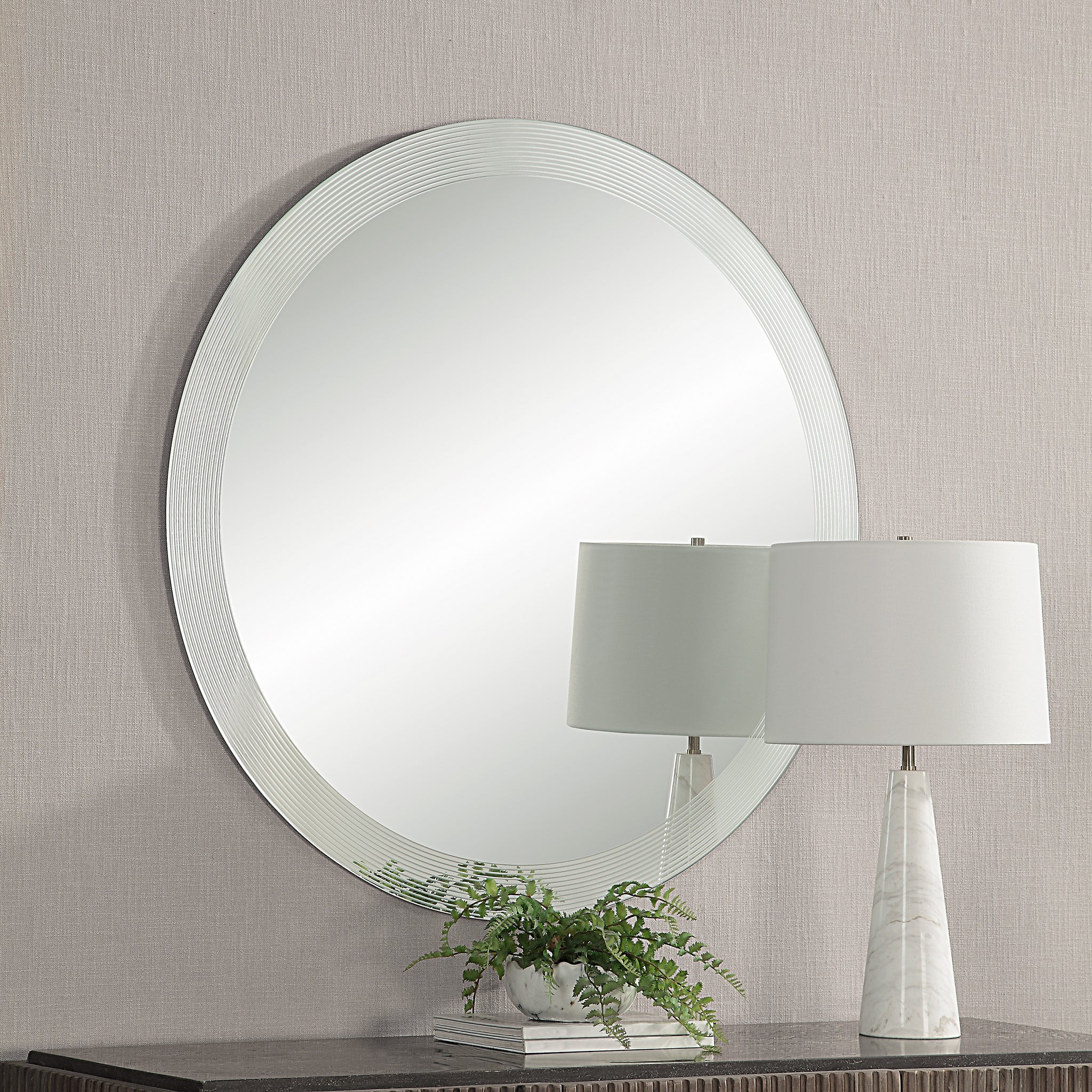 Osorno Wall Mirror displayed in a room with a lamp and plant on a table