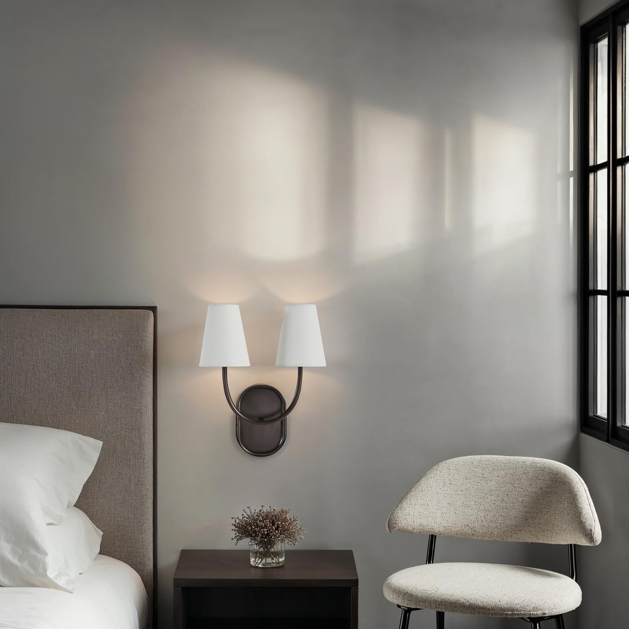 Megara wall sconce installed in a modern bedroom beside a bed and chair