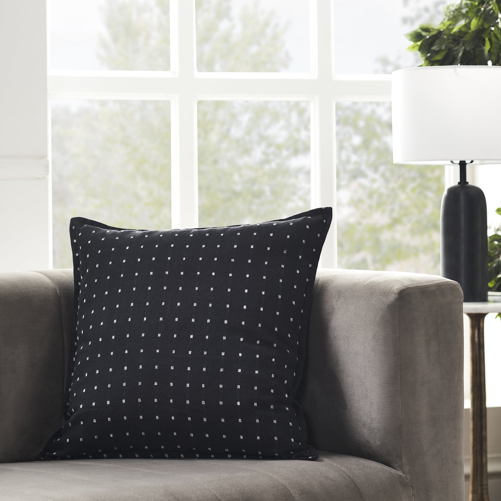 Brittany Indoor Pillow in black with white square pattern, placed on a gray sofa.