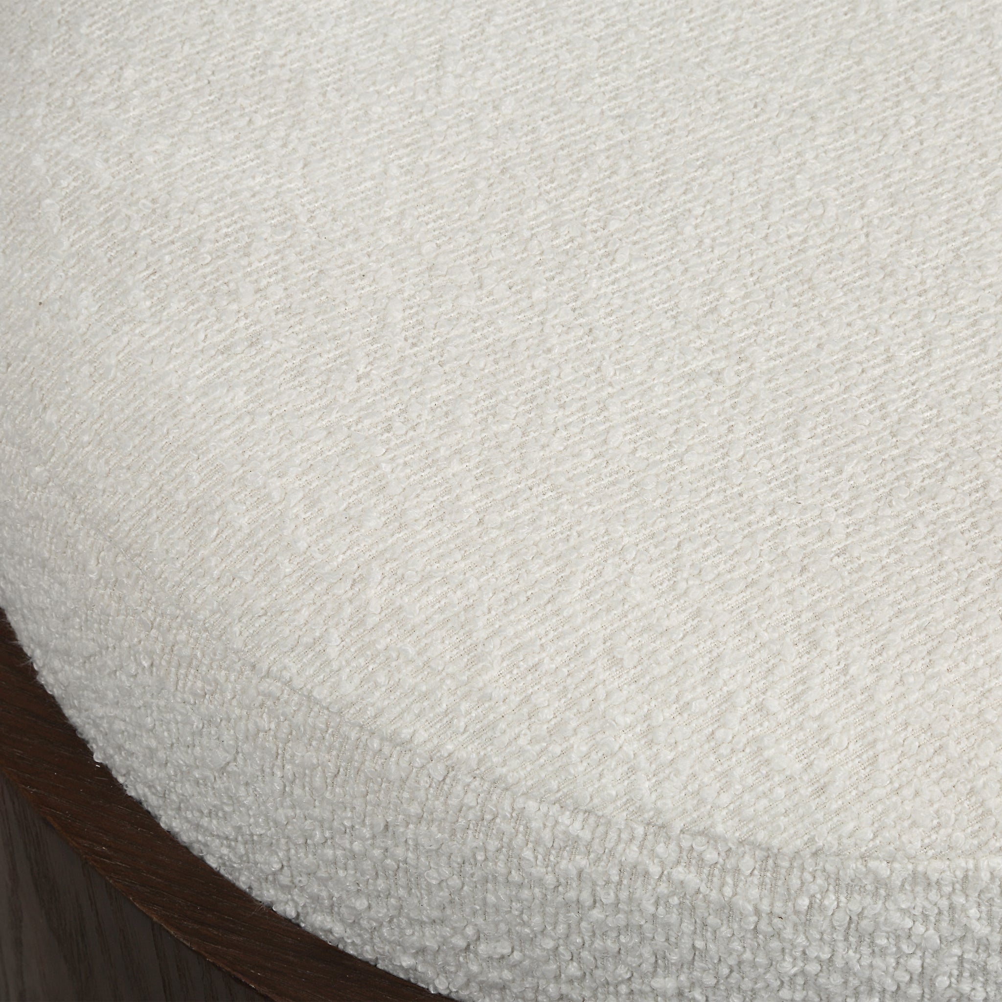 Capsula ottoman with a textured white fabric top and a wooden base, showcasing a close-up view of the surface.