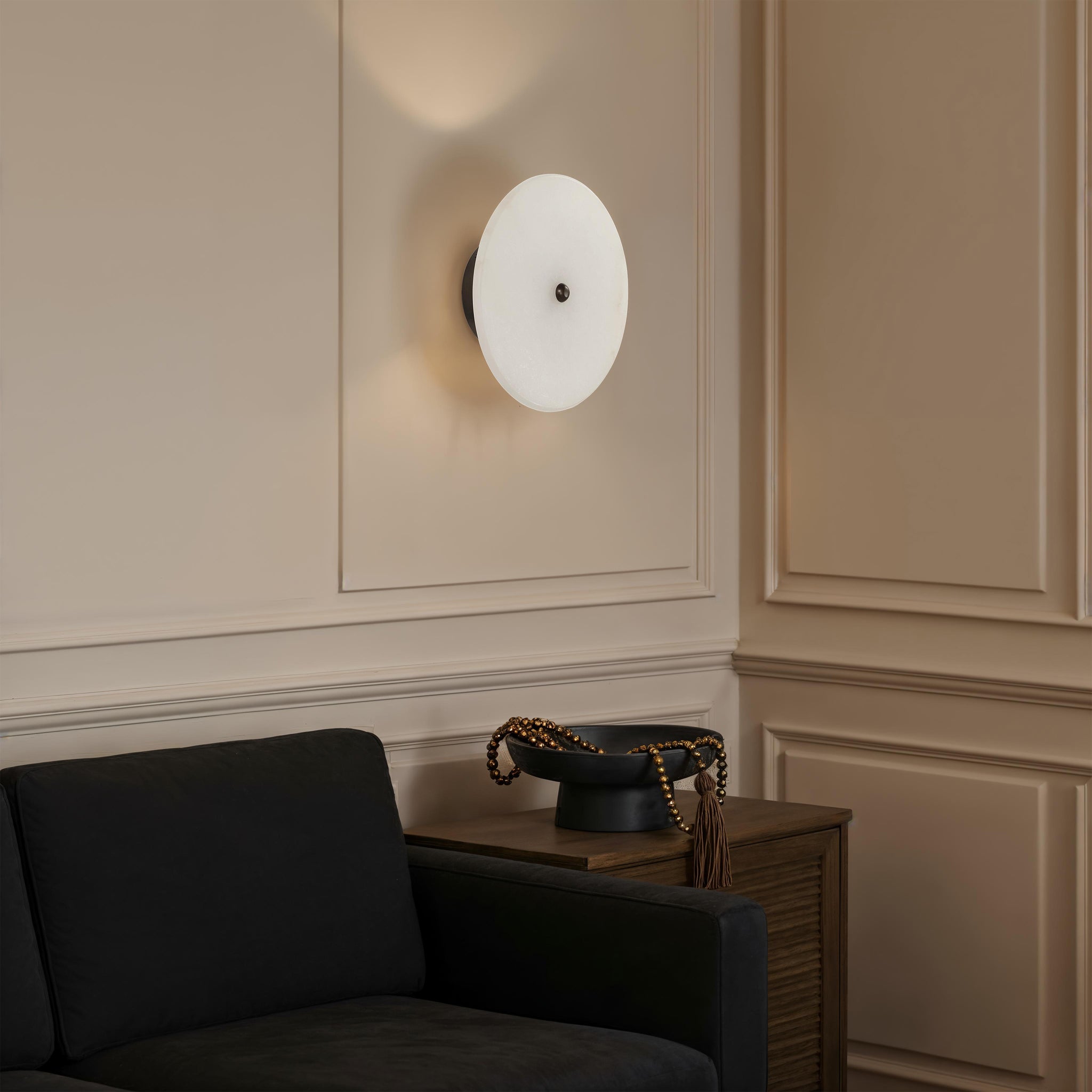 Lorenzo Wall Sconce mounted on a wall beside a black sofa and decorative bowl