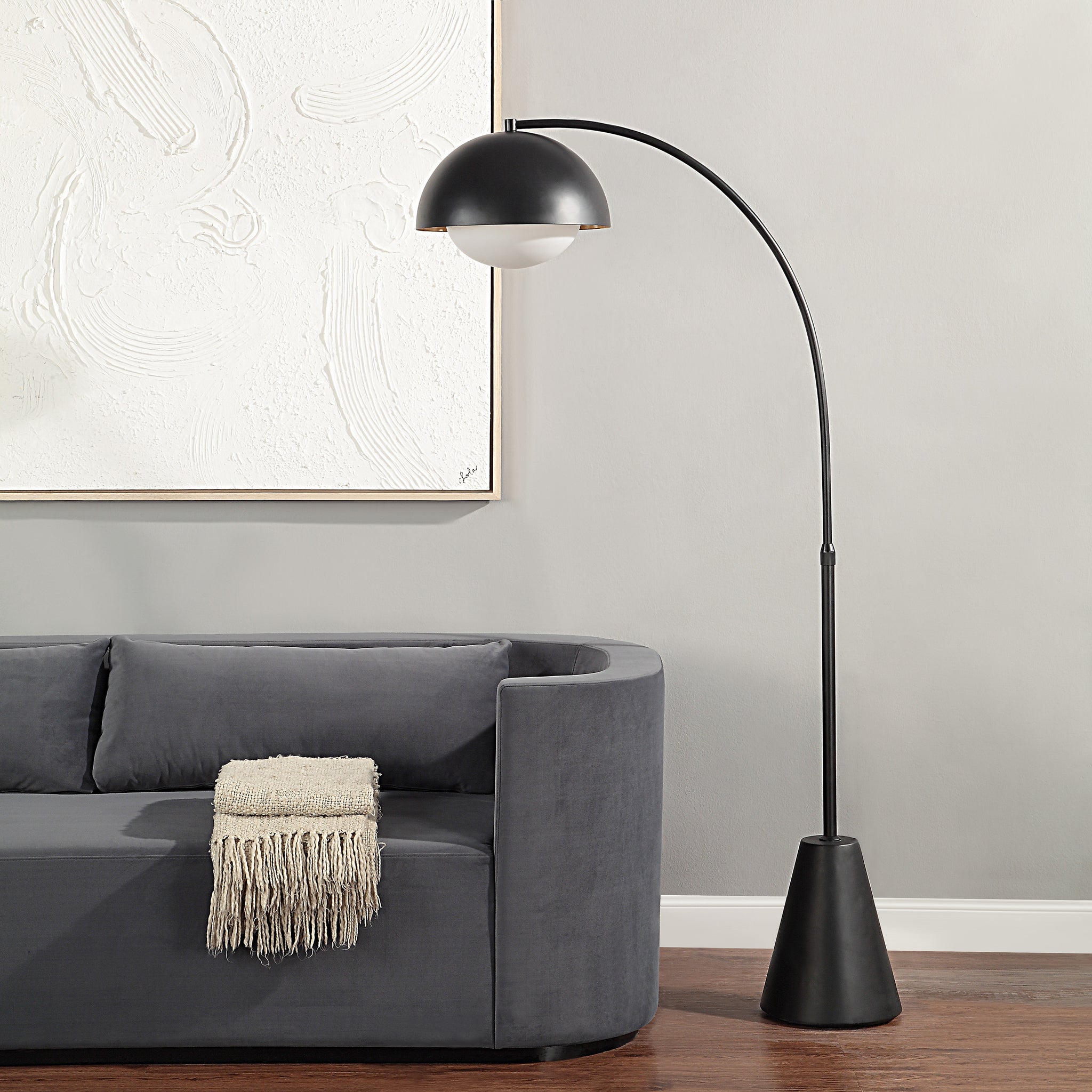 Cooke Floor Lamp positioned beside a gray sofa, with a black dome shade and white globe illuminating the space.
