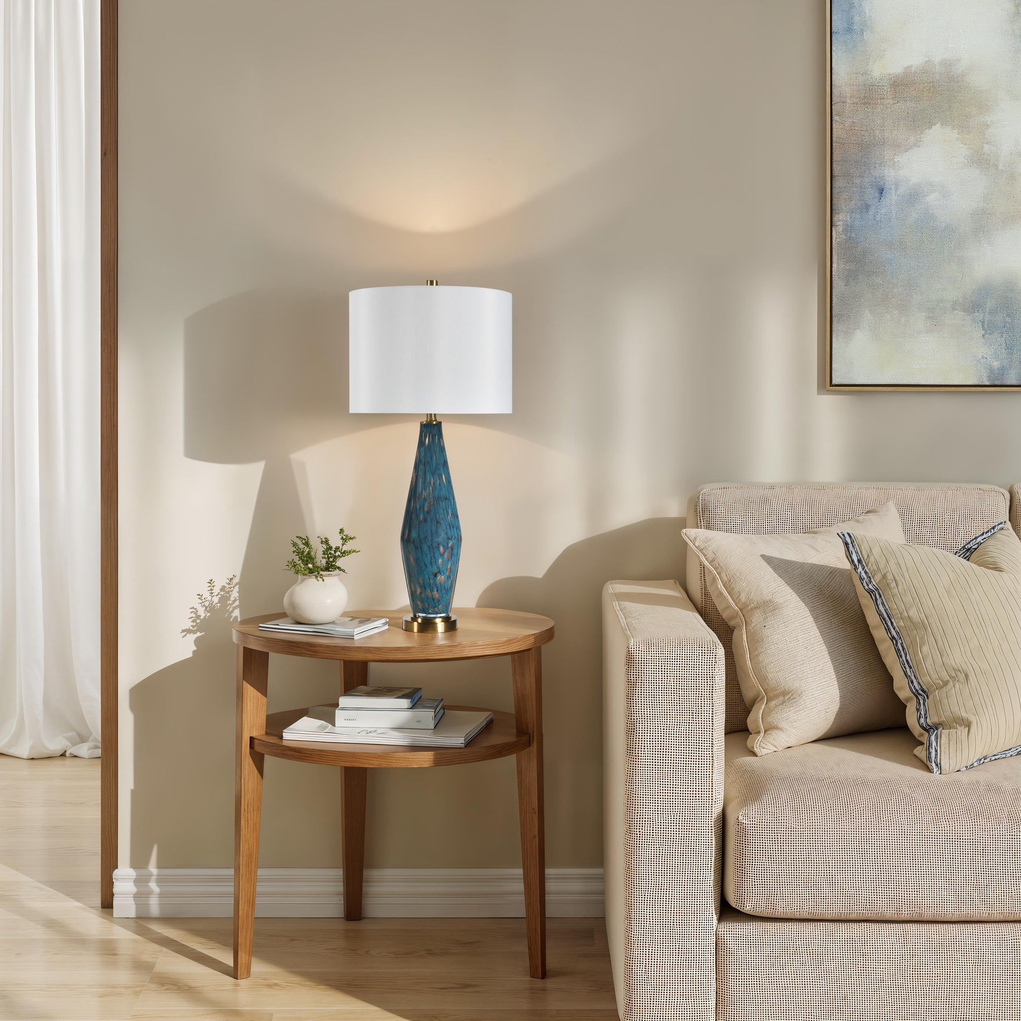 Milo Table Lamp on a round wooden side table next to a beige sofa, casting a warm light.