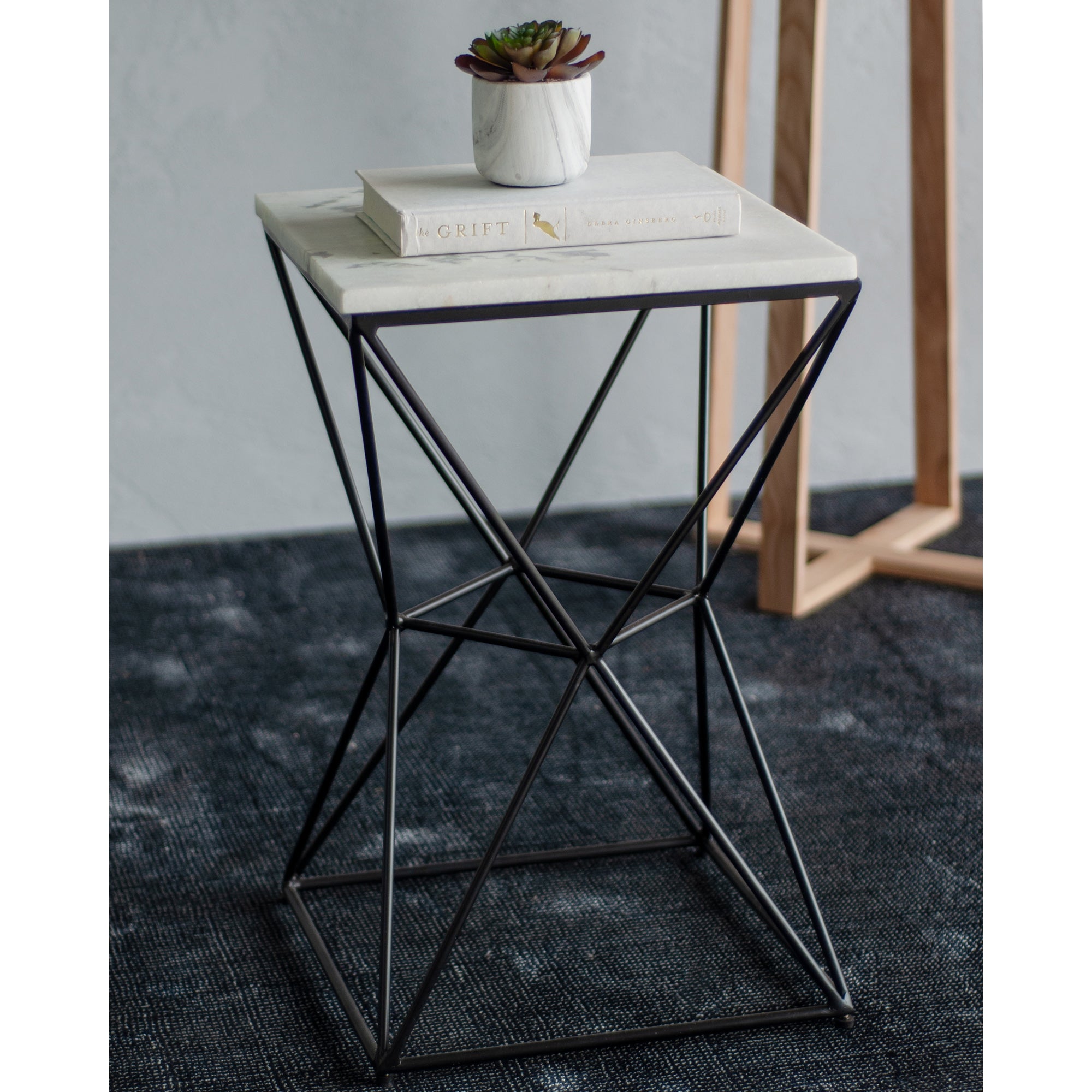 SYMMETRY table with a small plant and book on a white marble surface