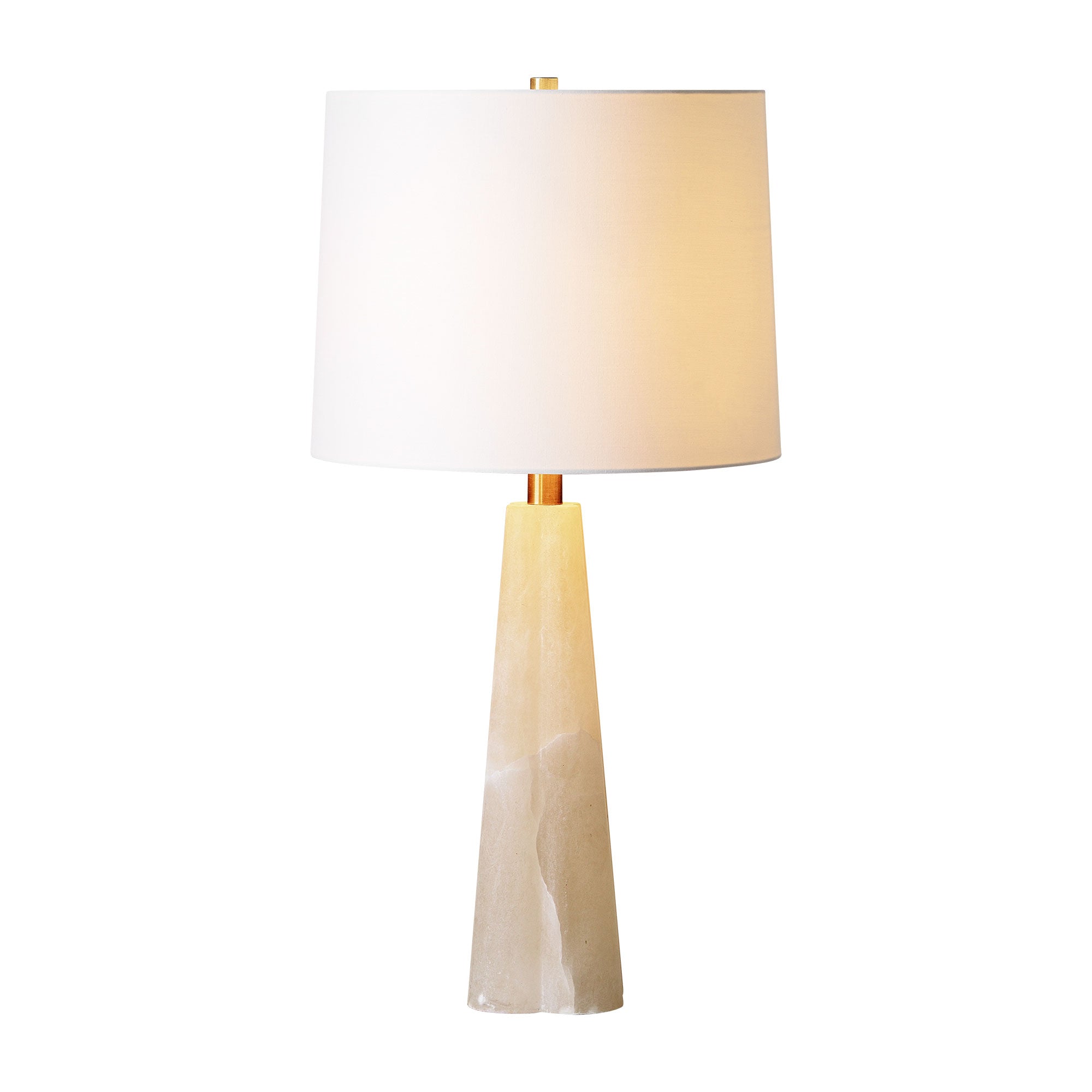 Rima Table Lamp illuminated, with a white shade and a light beige stone base.