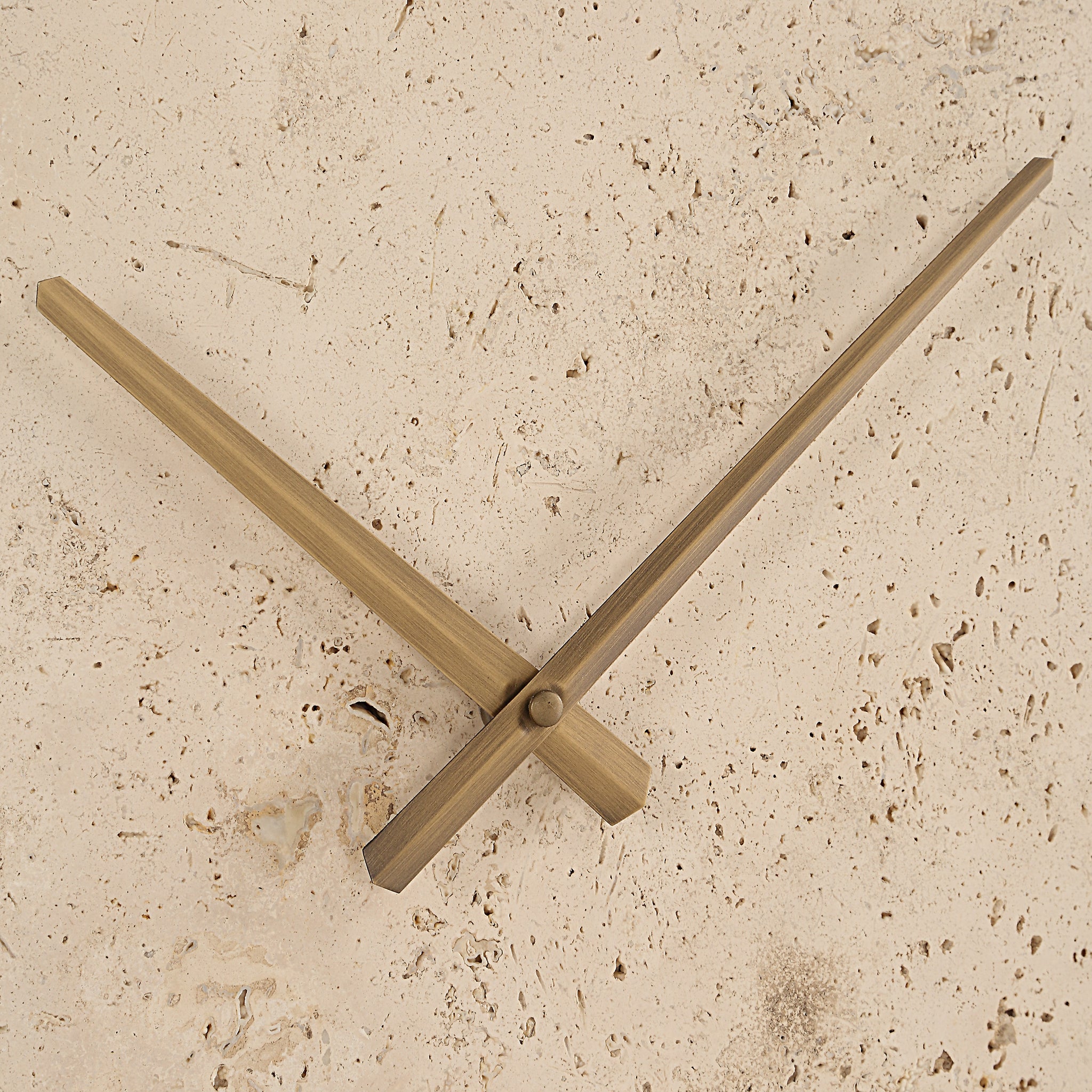 Detail view of Fusion book holder's bronze clock hands against a beige textured background.