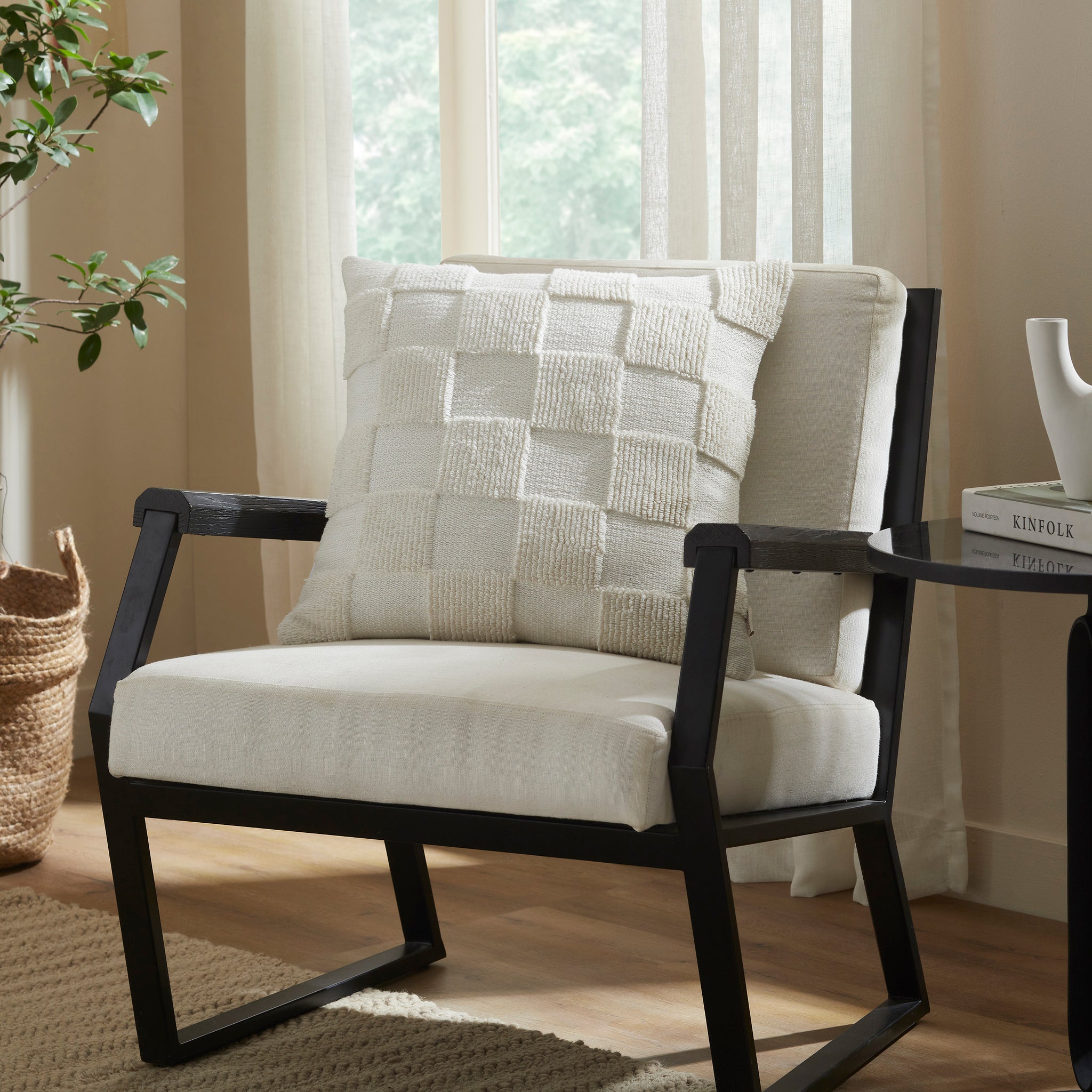 Terrah Indoor Pillow styled on a black armchair in a bright room