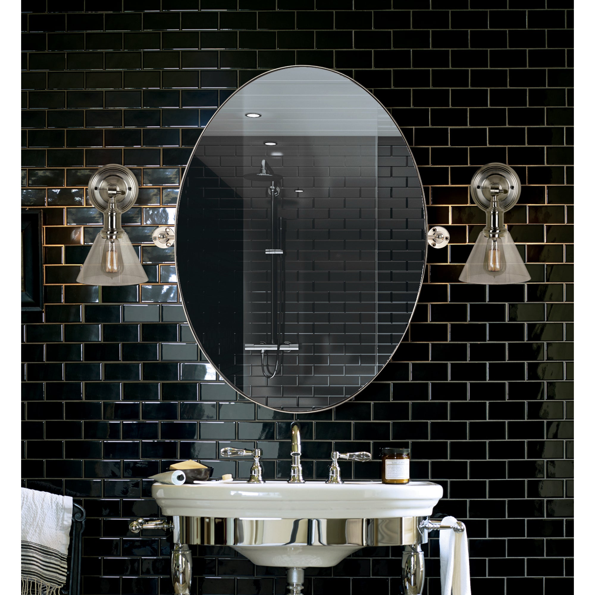 Azalea Wall Mirror installed in a modern bathroom with black tile backdrop