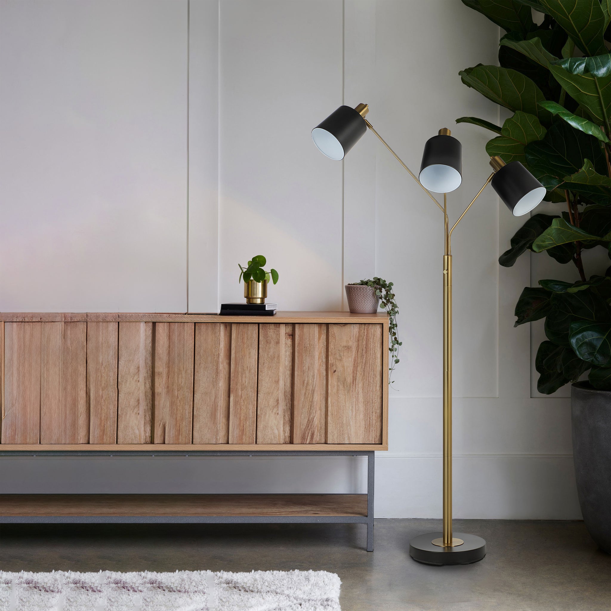 Meander floor lamp in a modern living room beside a wooden cabinet and potted plants.