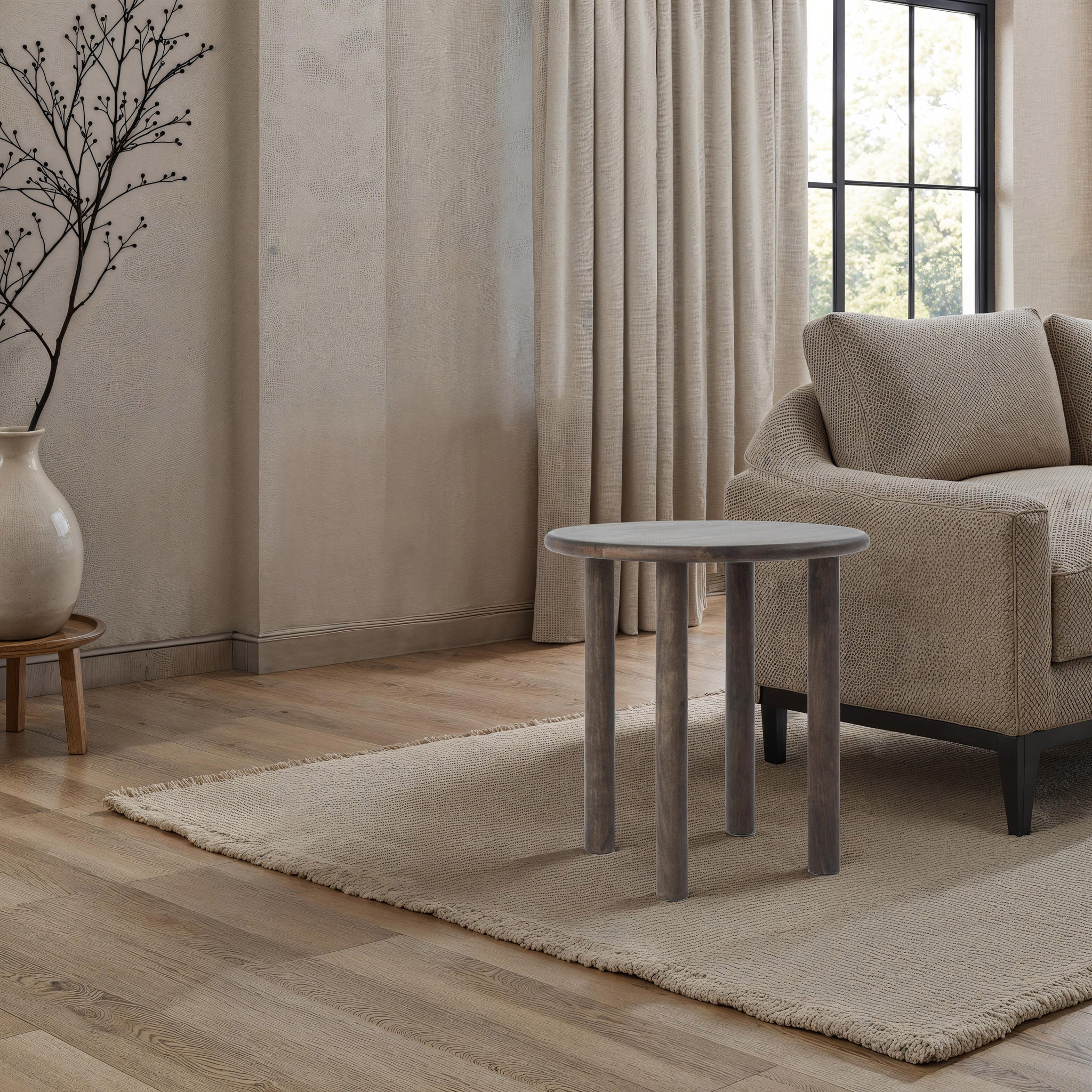 Cetus accent table placed in a living room setting beside a beige sofa and decorative vase.