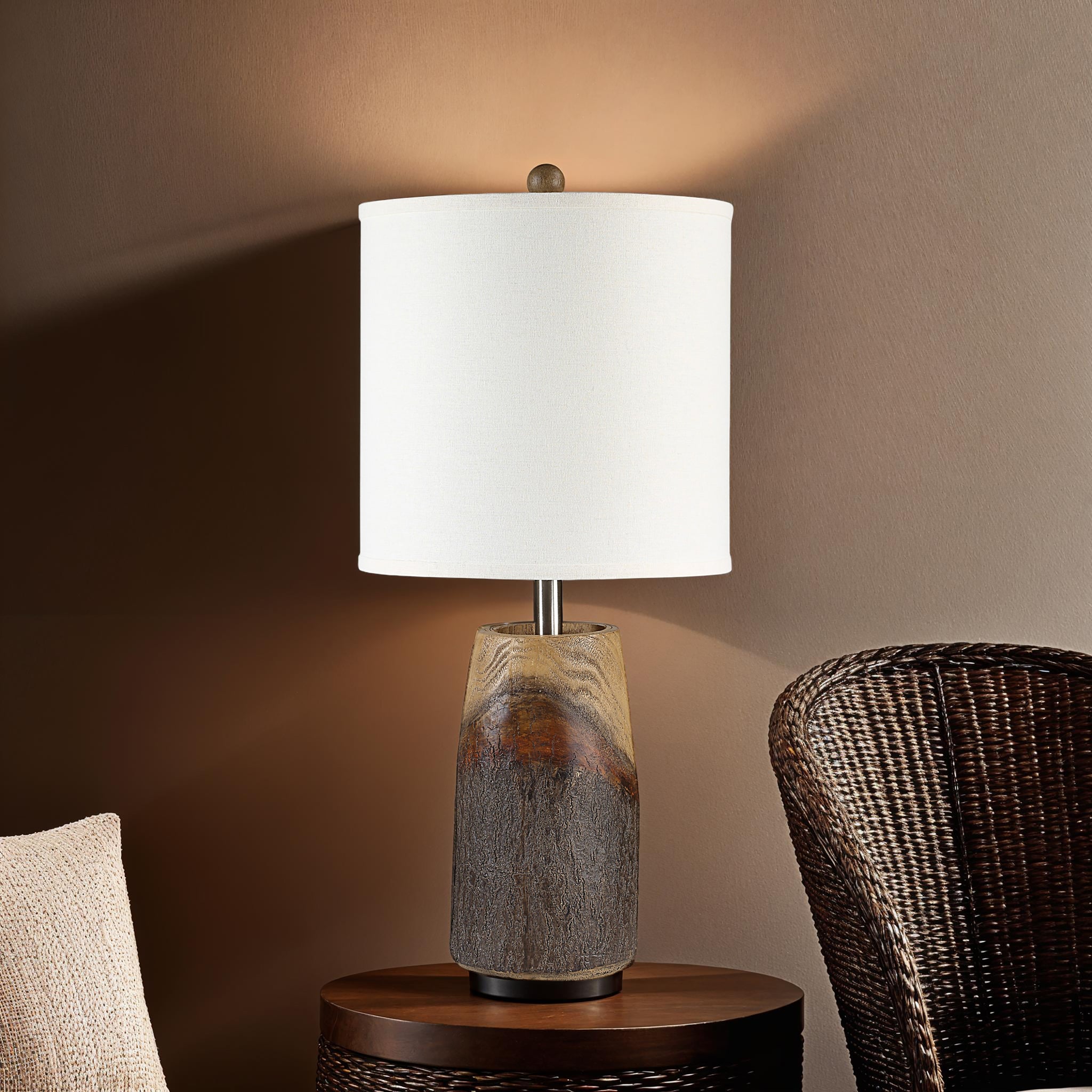 Vinca Table Lamp on a side table with a brown wall backdrop and a woven chair