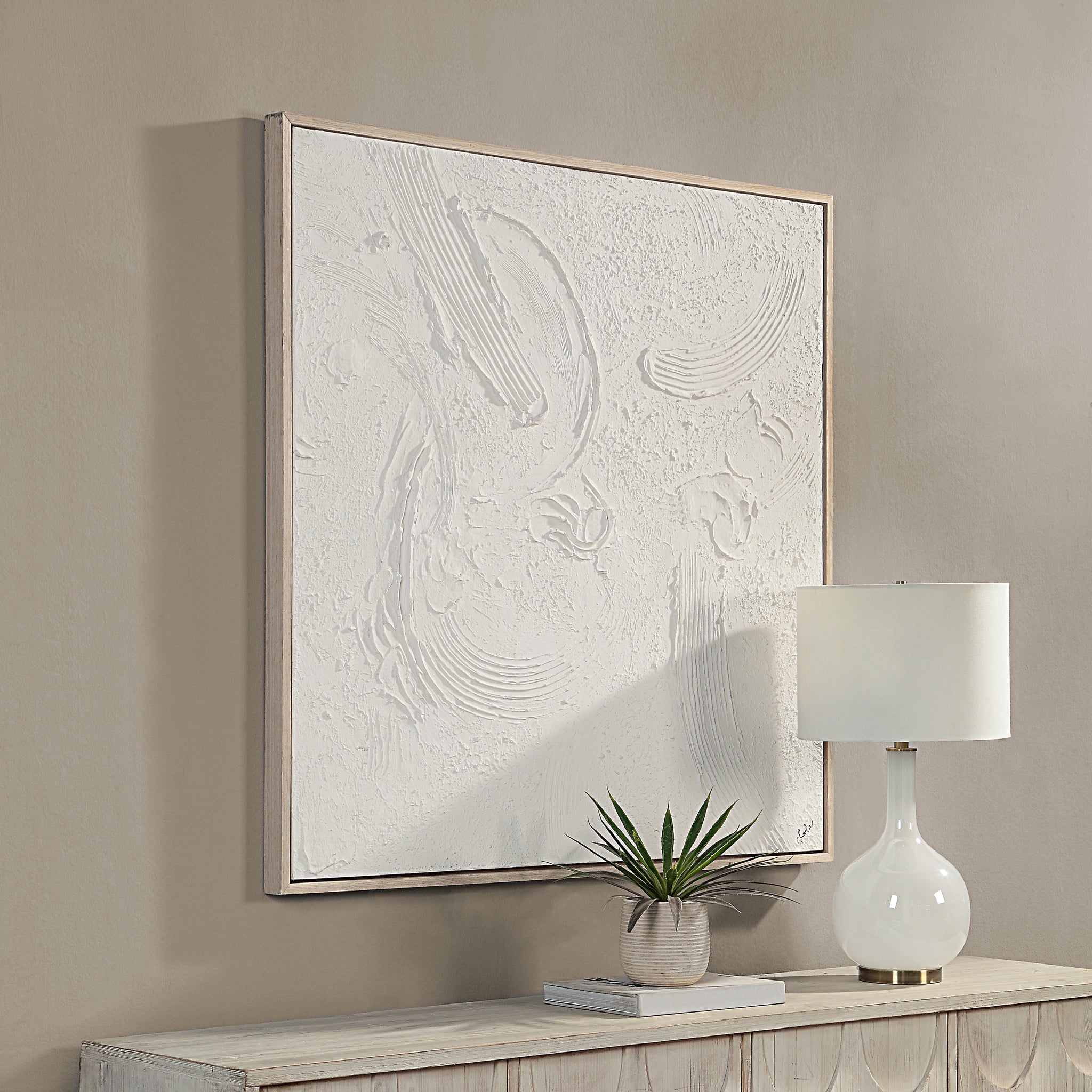 Luz canvas art by Renwil displayed on a wall above a table with a lamp and plant.