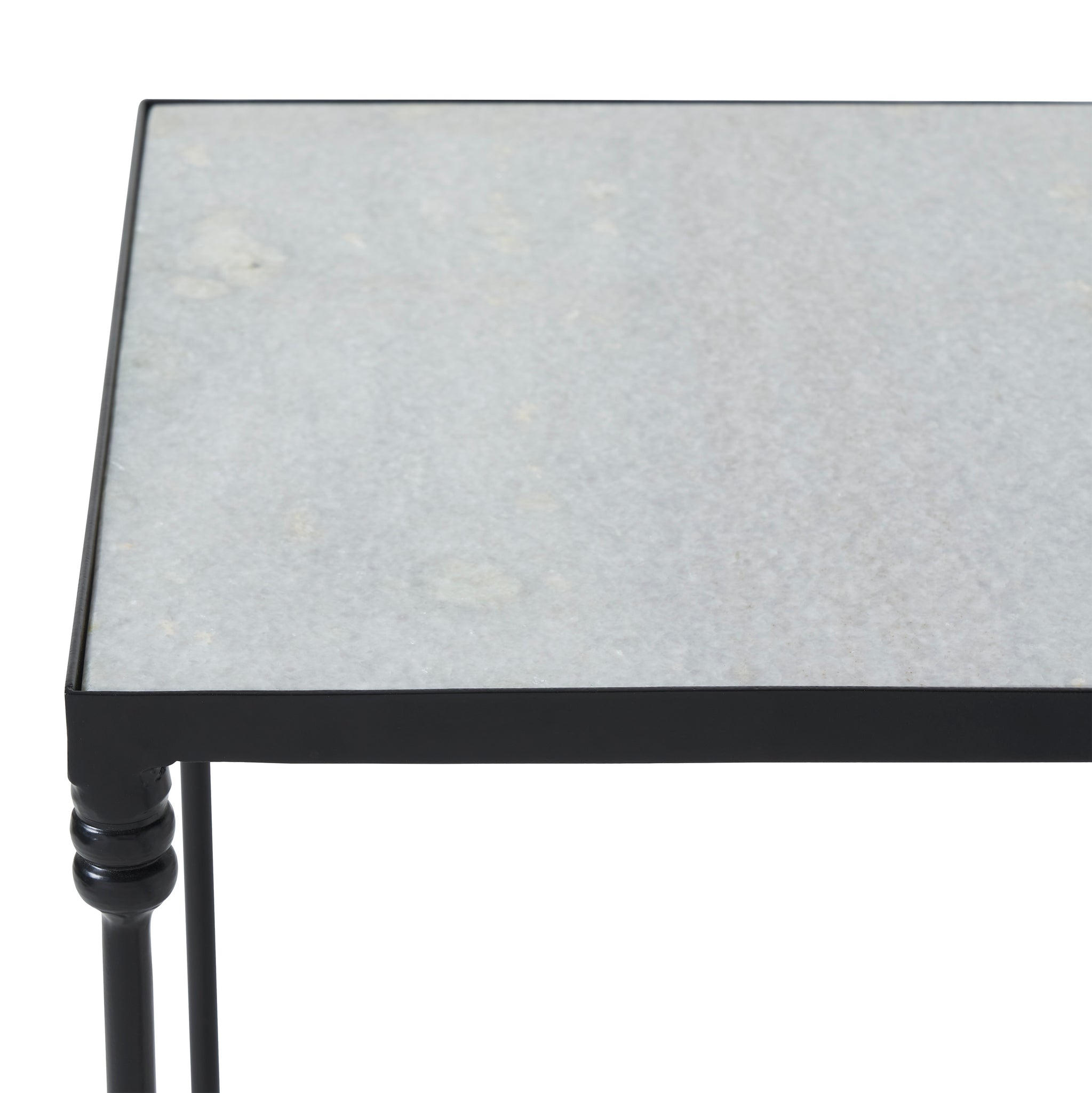 Close-up of the Giulia table's gray stone top and black metal edges.