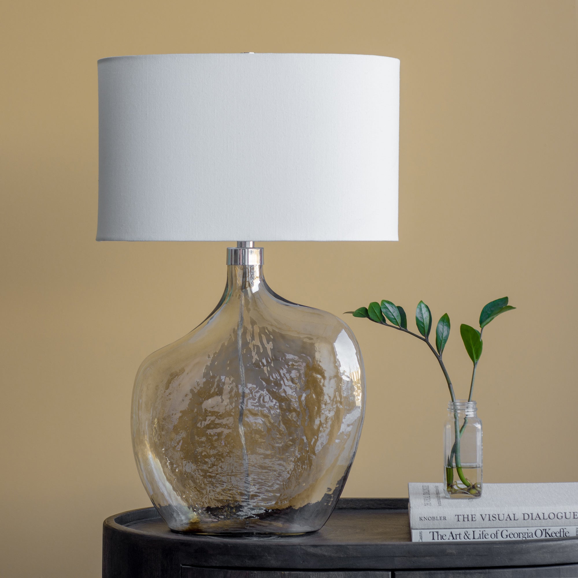 Benedek Table Lamp on a table with a white shade and a gold glass base