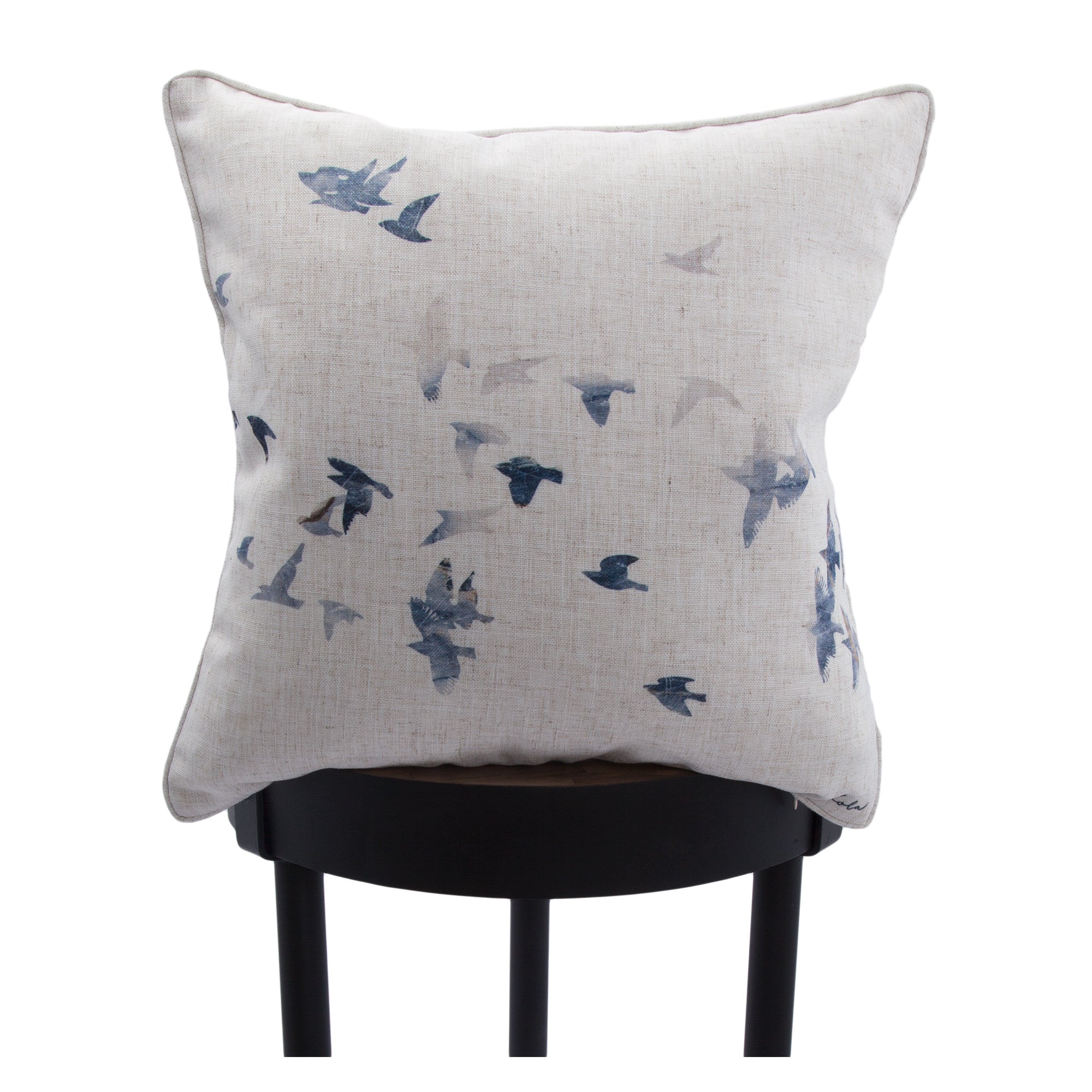 Flight indoor pillow with a bird design, displayed on a black stool.
