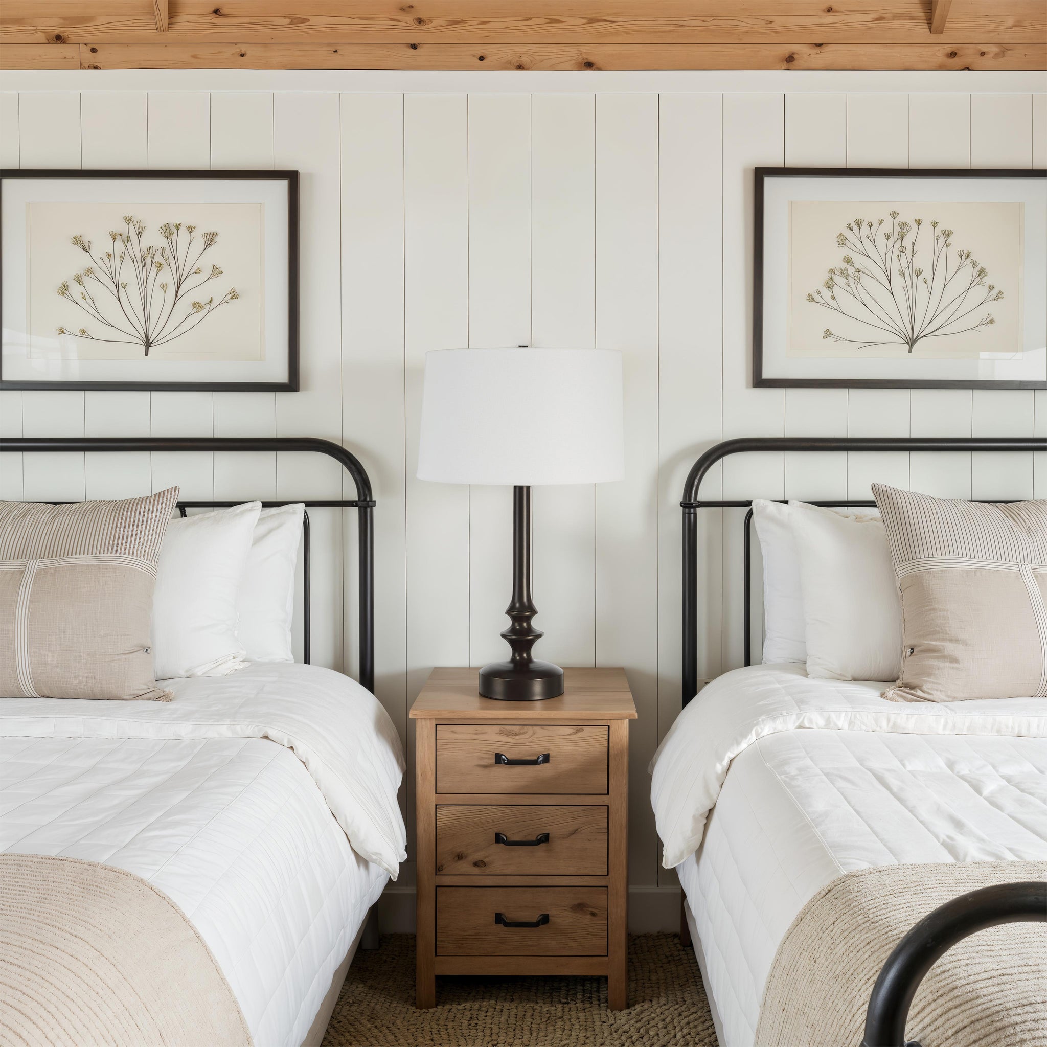 Zyra Table Lamp on a nightstand between two beds, cozy bedroom setting with artwork.