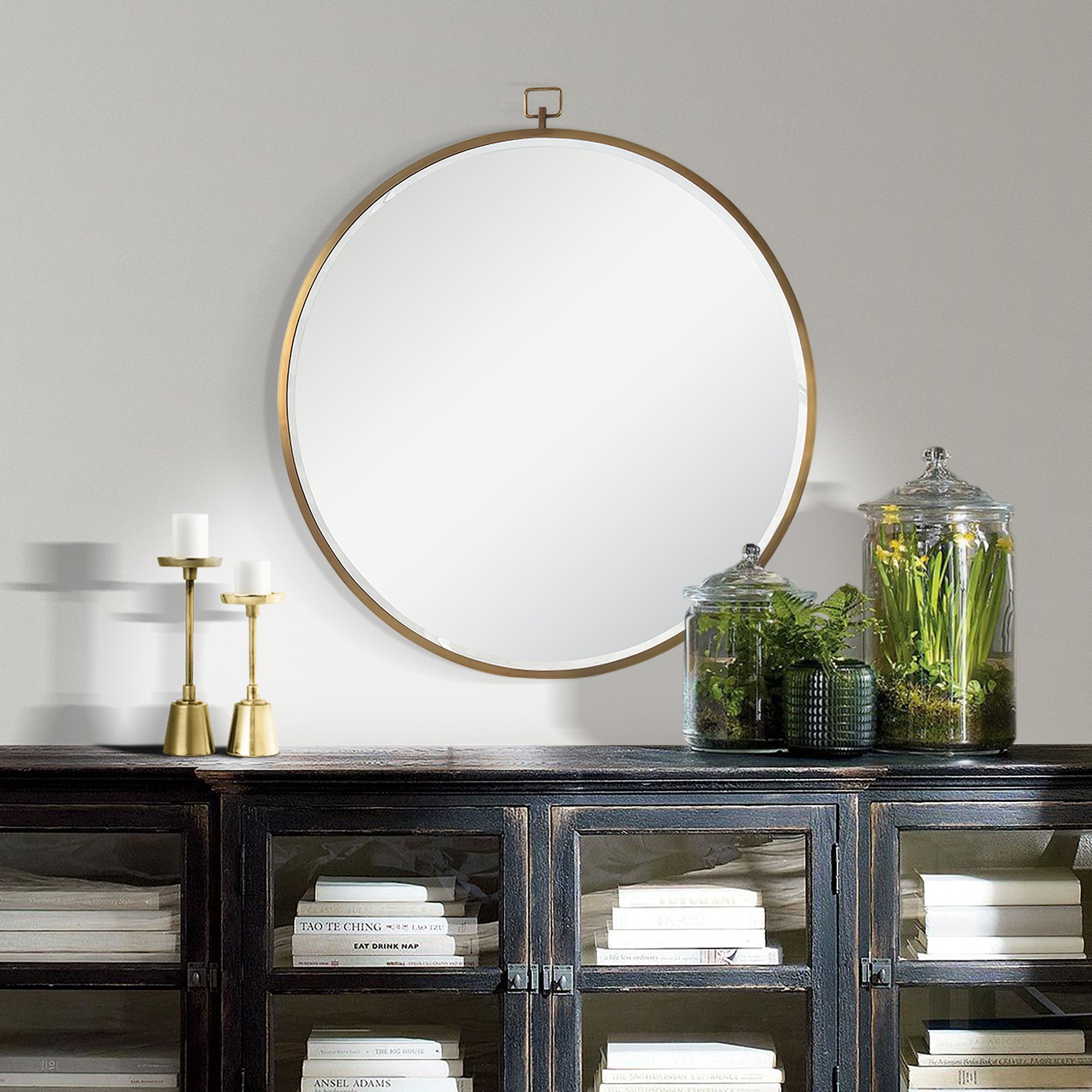 Azam Wall Mirror displayed on a wall above a dark wooden cabinet with decor items.
