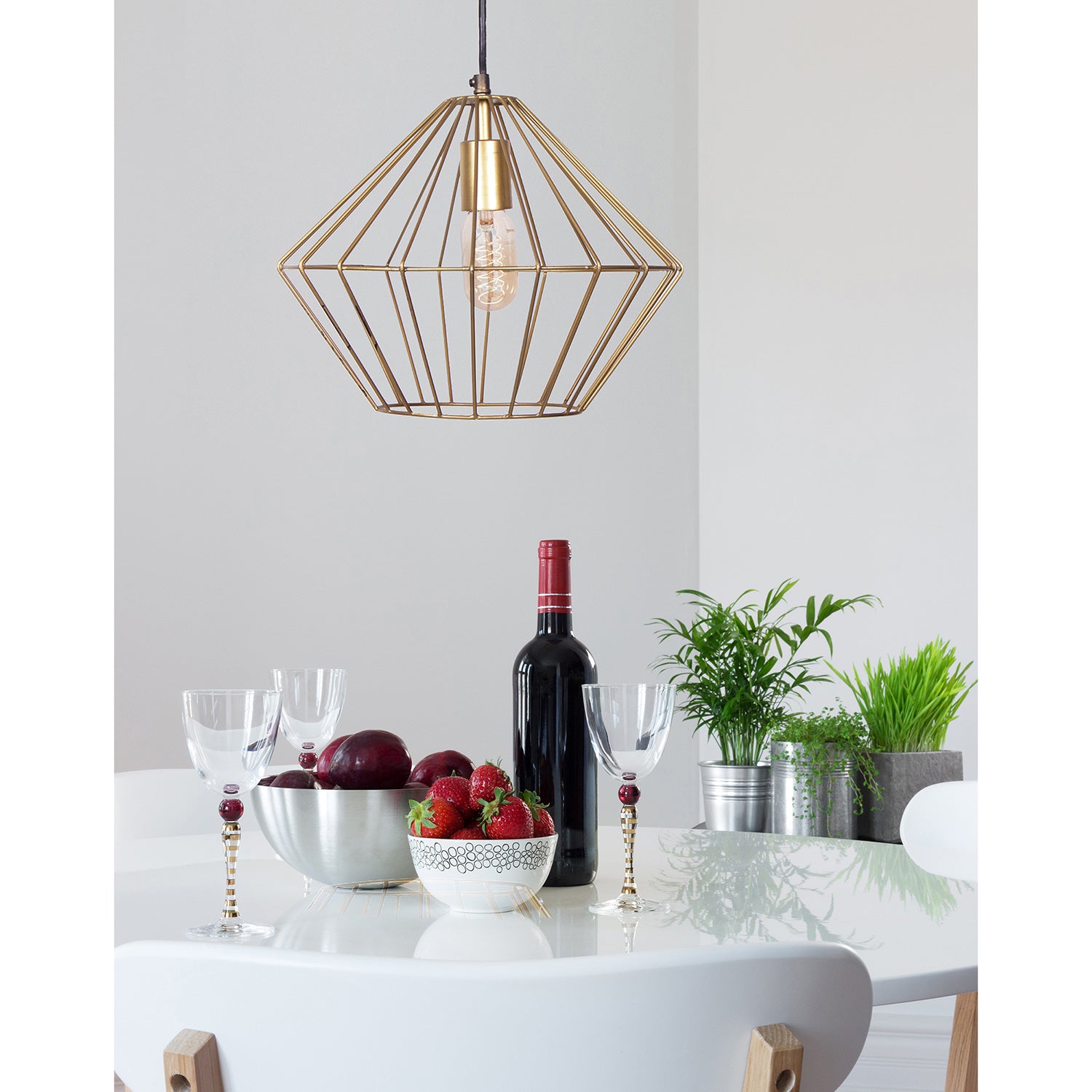 Empire Ceiling Fixture above a dining table set with wine, glasses, and fruit, featuring a gold geometric design.