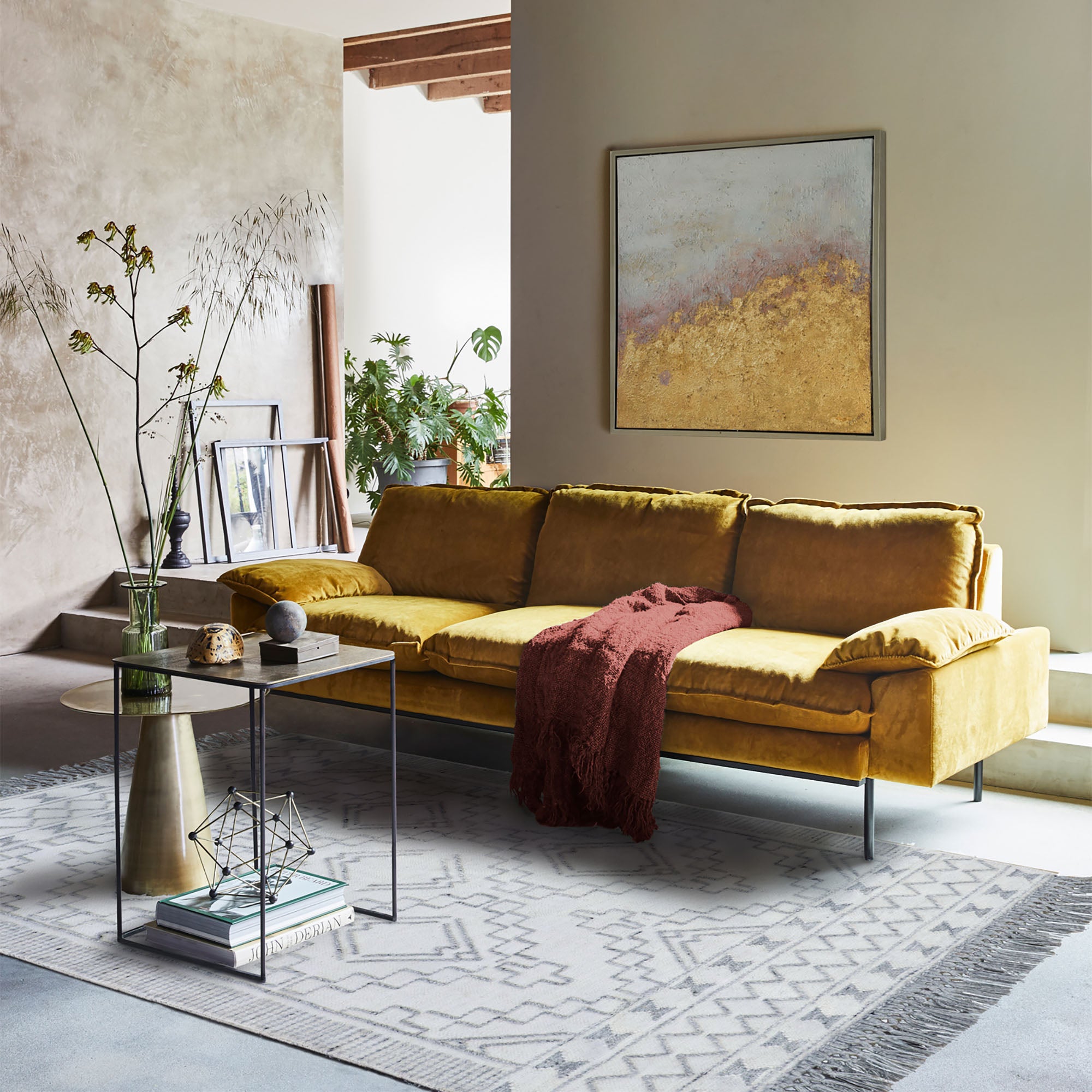 Threefold Indoor Aluminum Table beside a mustard yellow sofa in a stylish living room setting.