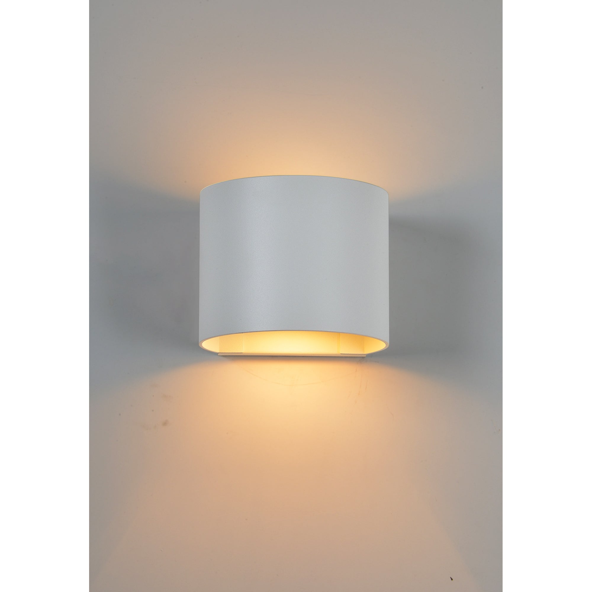 Zak Wall Sconce in white, casting light upwards and downwards on a wall.