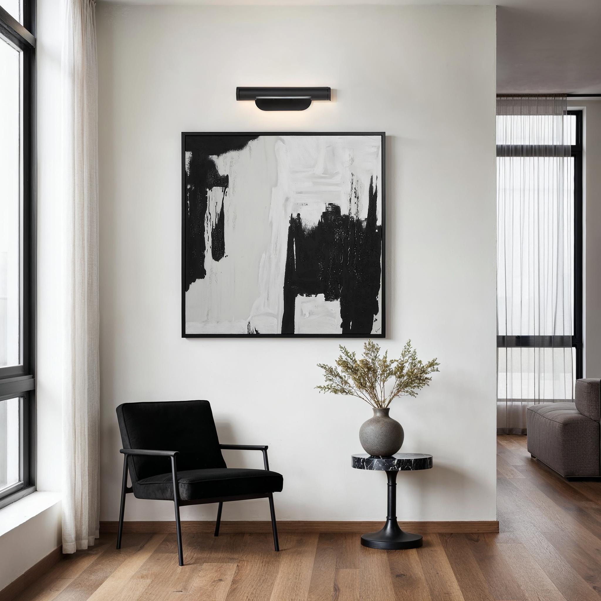 Oleandro Wall Sconce in a modern interior setting above a black and white artwork.