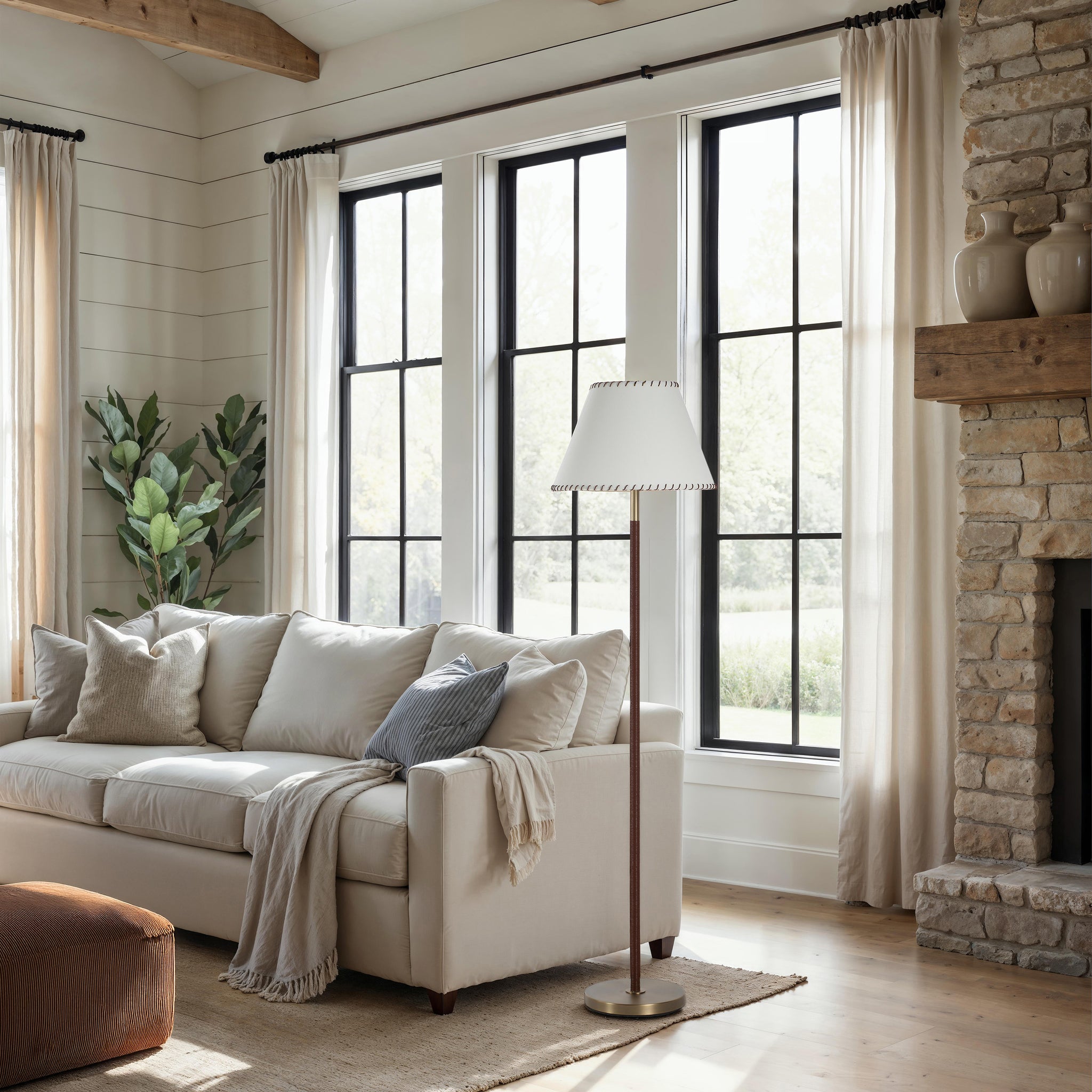 Elea floor lamp beside a light-colored sofa in a bright living room with large windows.