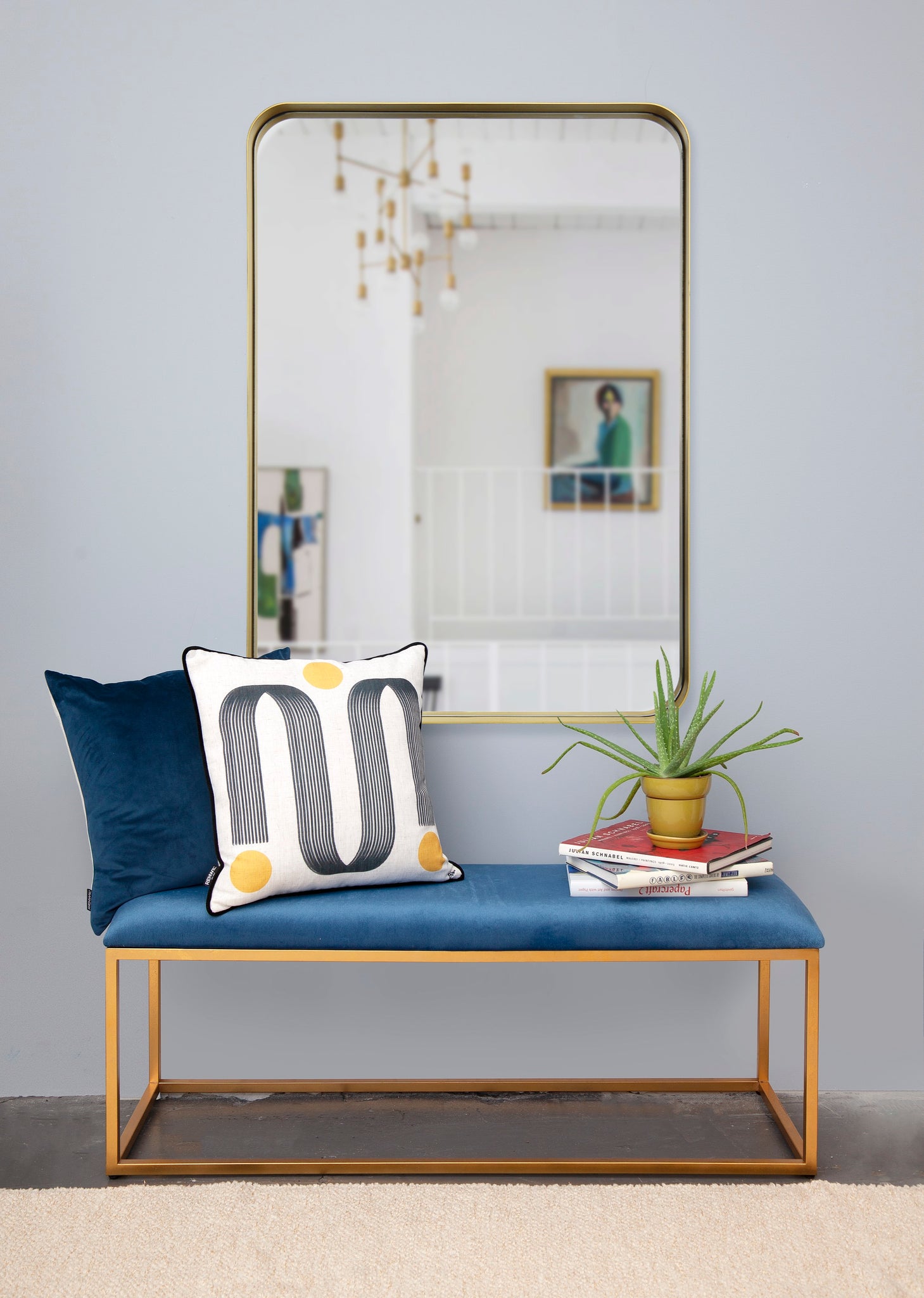 Barton Wall Mirror above a blue bench with decorative pillows and a potted plant