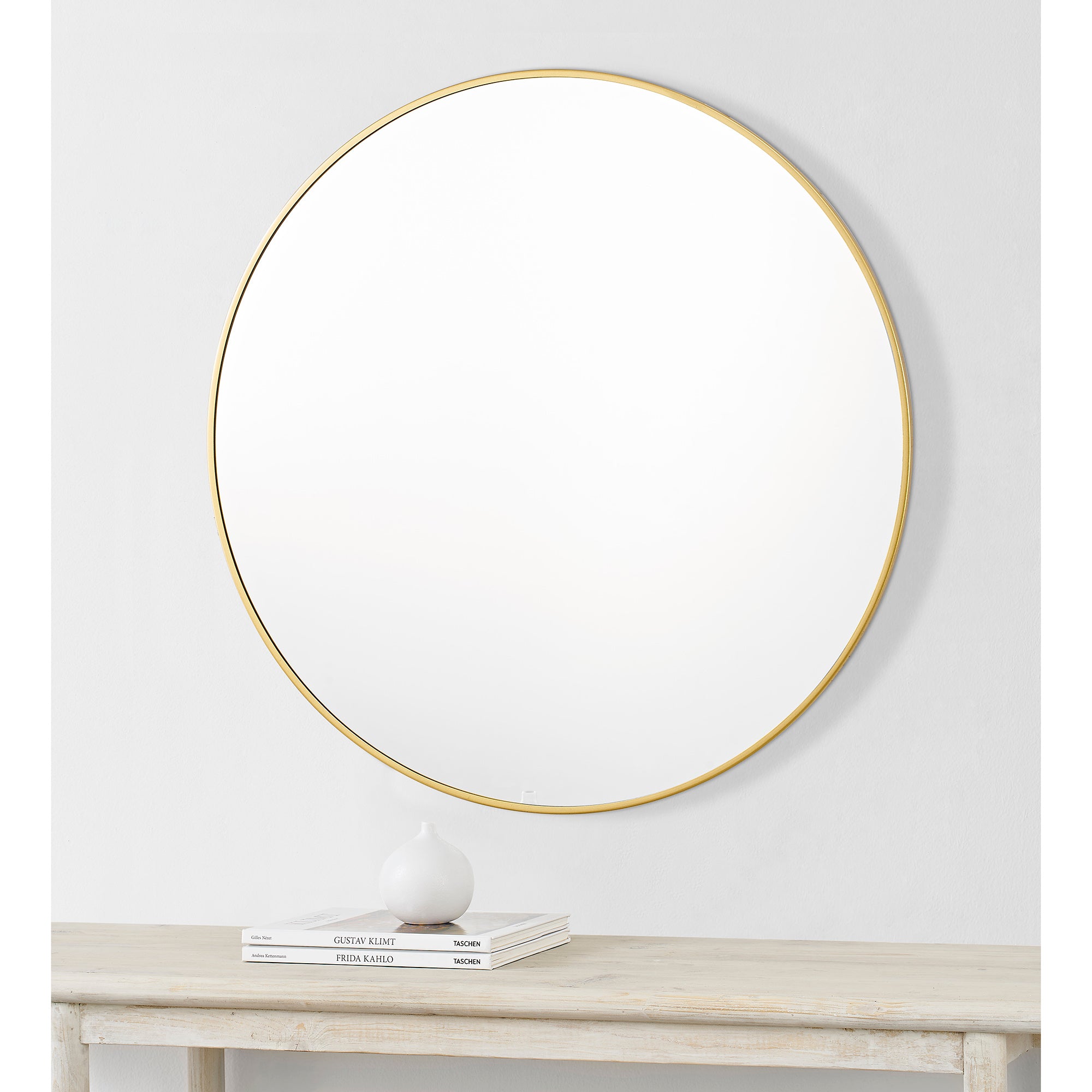 Alegre Wall Mirror mounted on a wall above a table with decor.