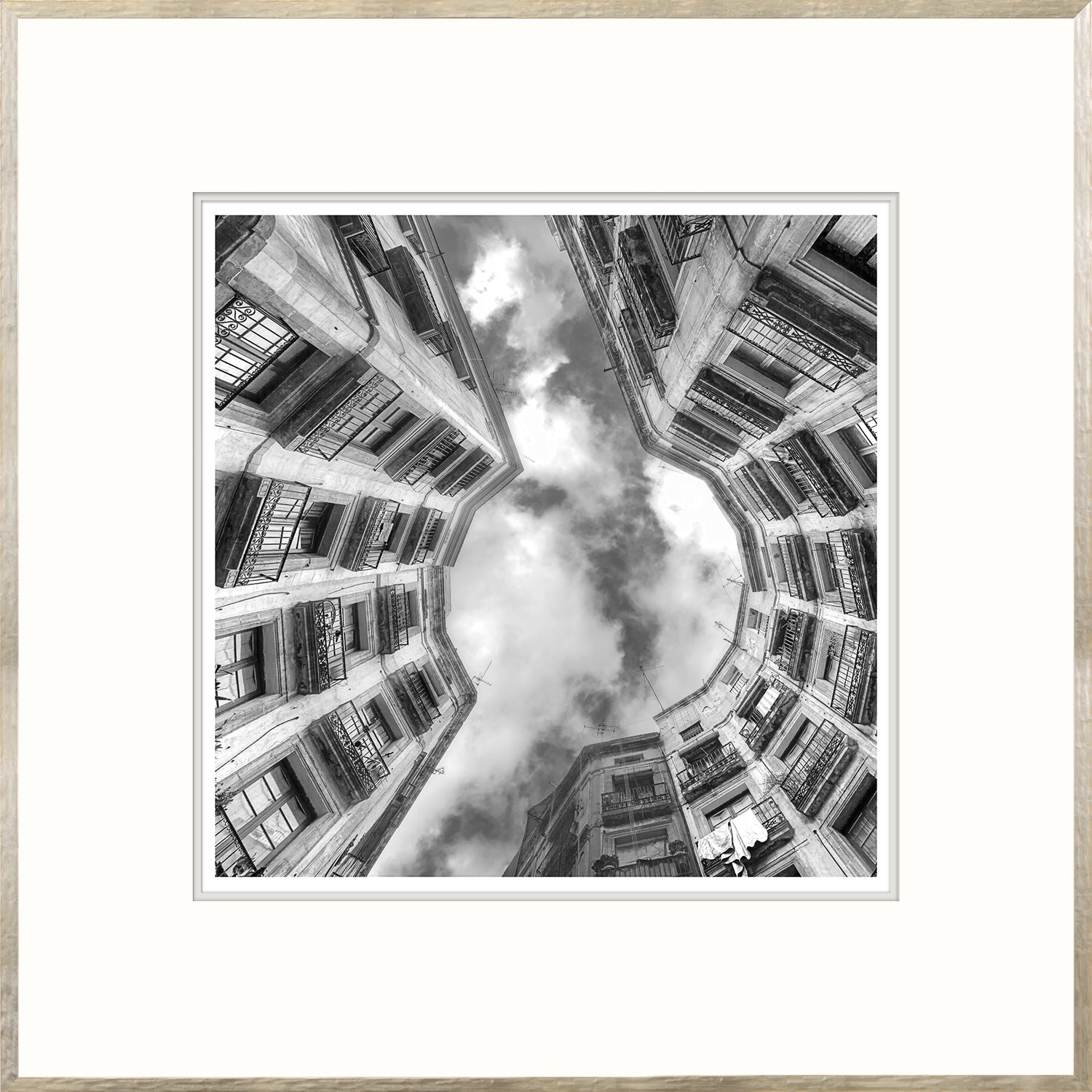 Upward Focus wall art featuring a black and white view of buildings and clouds from below.