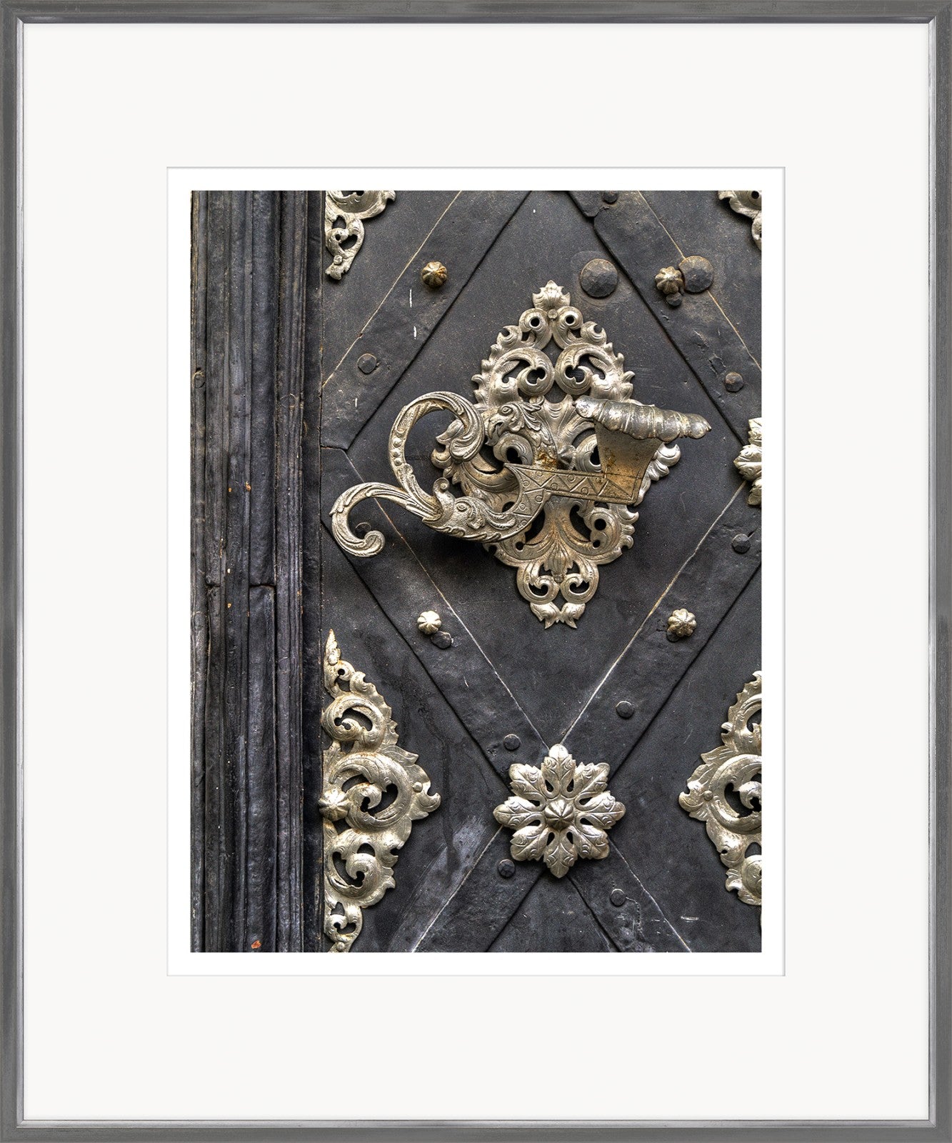 European Door Detail IV wall art featuring ornate silver hardware on a dark wooden door.