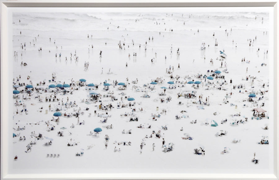 Teal Umbrellas wall art featuring a beach scene with numerous teal umbrellas and people on a white sandy beach.