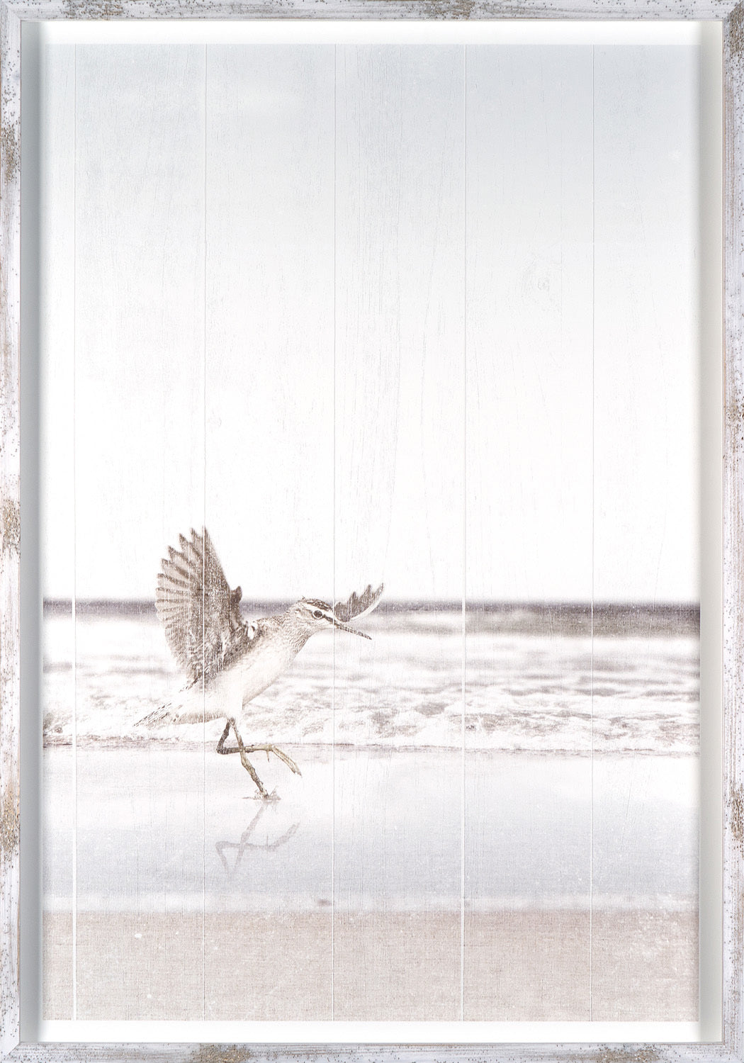 At Surfs Edge I wall art featuring a bird on the beach with ocean waves, framed in white wood.