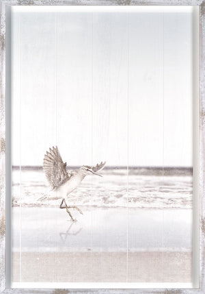 At Surfs Edge I wall art featuring a bird on the beach with ocean waves, framed in white wood.