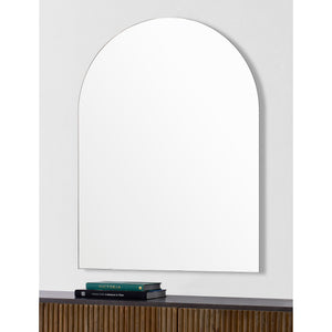 Aldrin mirror mounted on a wall above a wooden shelf with books.