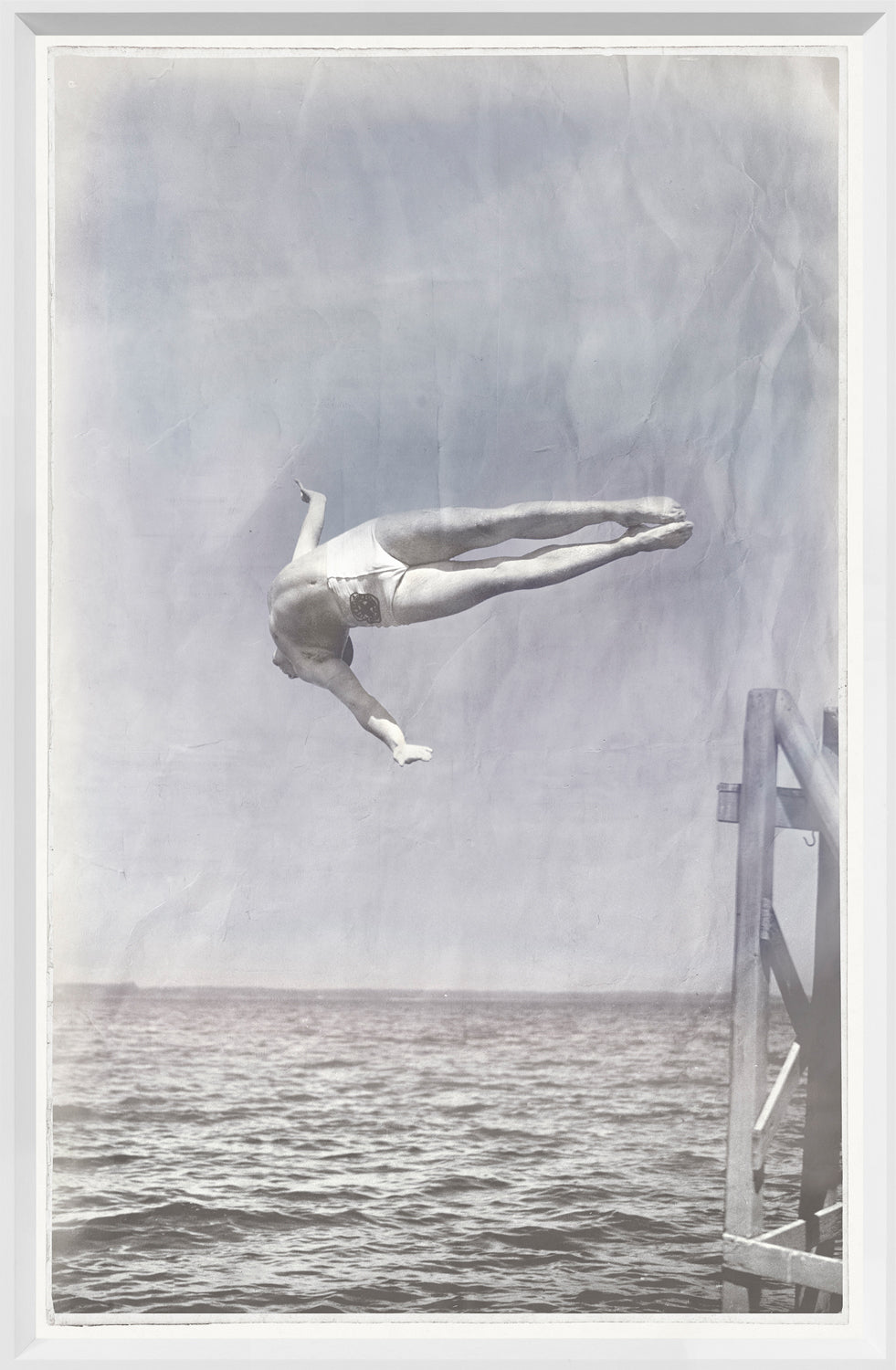 Indigo Stained – Mid Dive, a vintage-style wall art featuring a diver mid-air above water, in a faded blue and gray color palette.