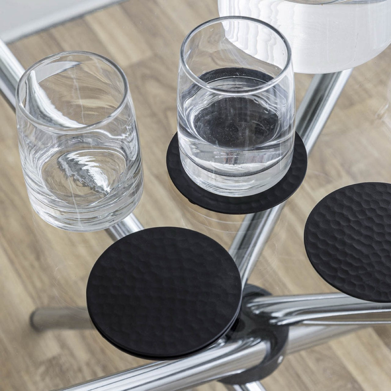 Black round coasters on a chair with glasses of water.