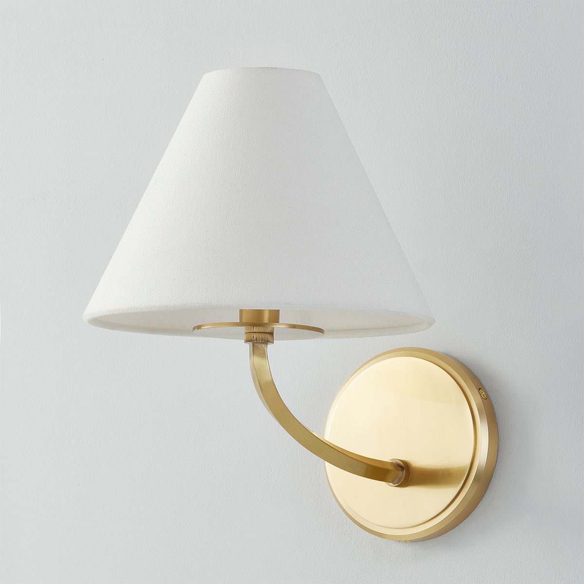 Stacey Wall Sconce in aged brass shown from the front to reveal the arm curve and shade silhouette.